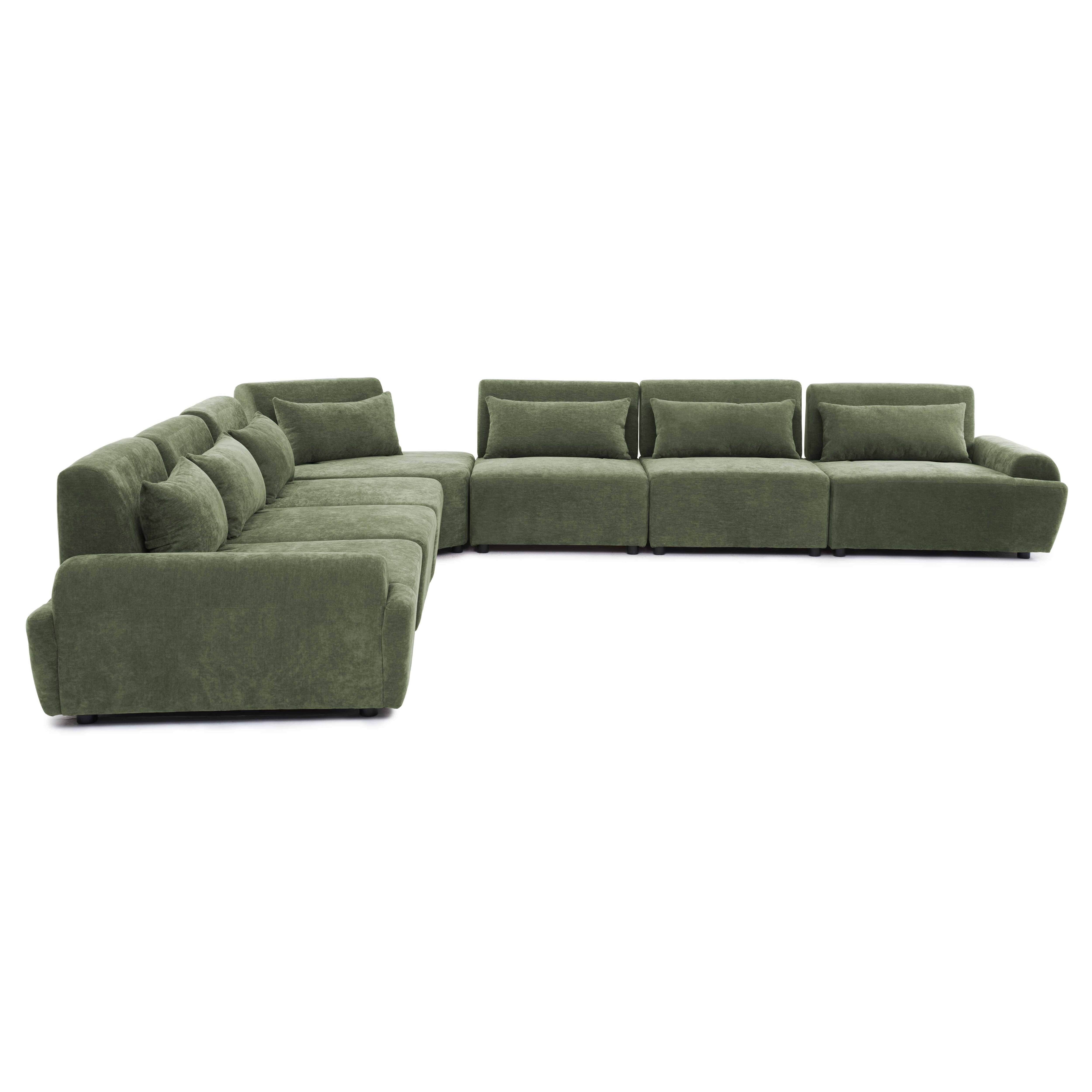 Ein grünes Modulsofa mit mehreren Kissen, das auf weißem Hintergrund steht.