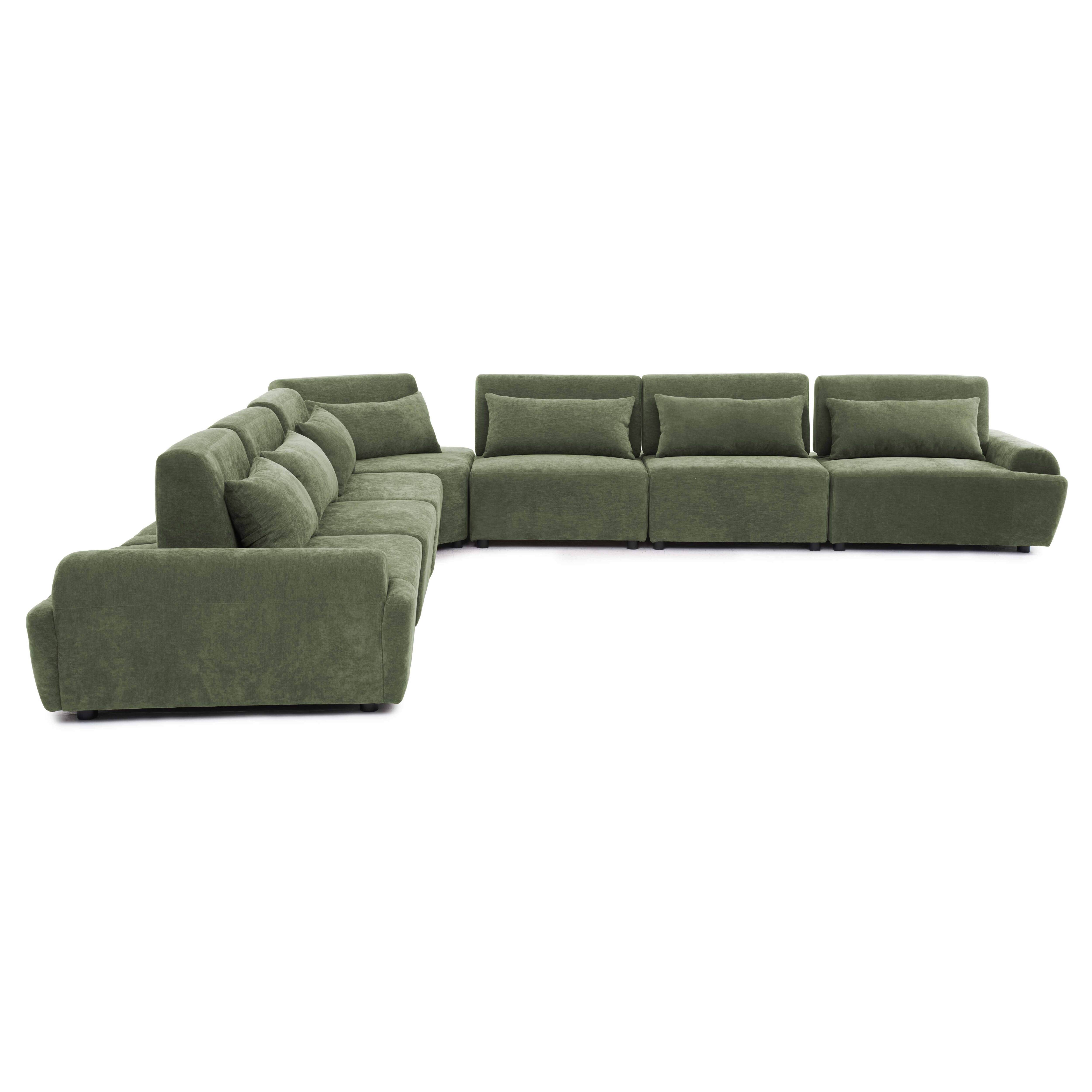 Ein grünes Ecksofa mit mehreren Kissen auf weißem Hintergrund.
