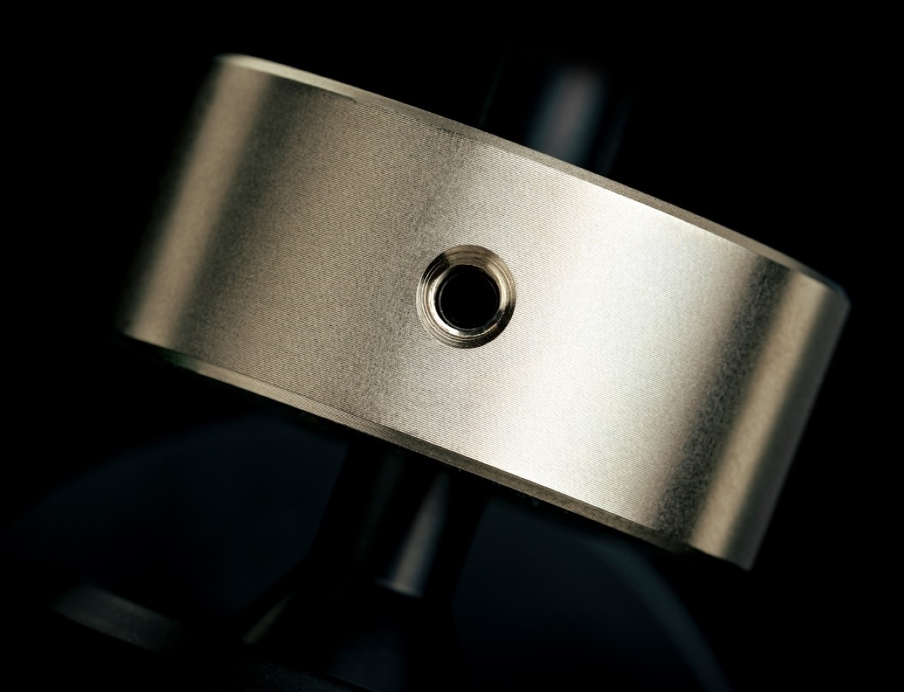 Srebrny cylinder z otworem na czarnym tle.