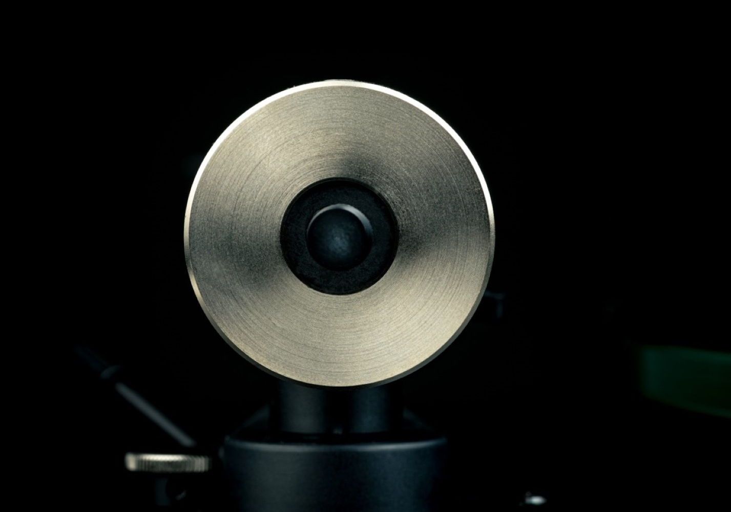 Zbliżenie metalowego ramienia gramofonu na czarnym tle.