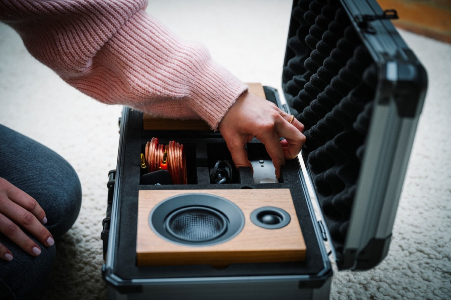 Osoba pakująca głośniki i kable do walizki z wyściółką piankową.