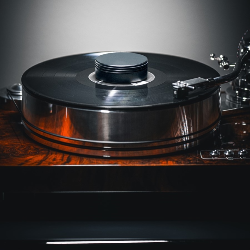 Zbliżenie gramofonu winylowego z czarną płytą na drewnianej podstawie.