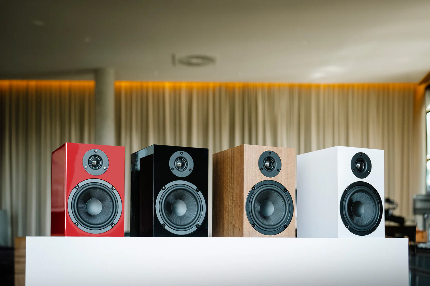 Cztery głośniki ustawione w rzędzie: czerwony, czarny, drewniany i biały.