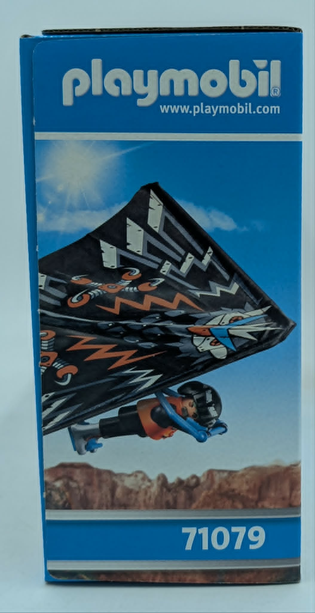Playmobil-Karton mit Spielzeugfigur mit Drachen-Gleiter über felsiger Landschaft.