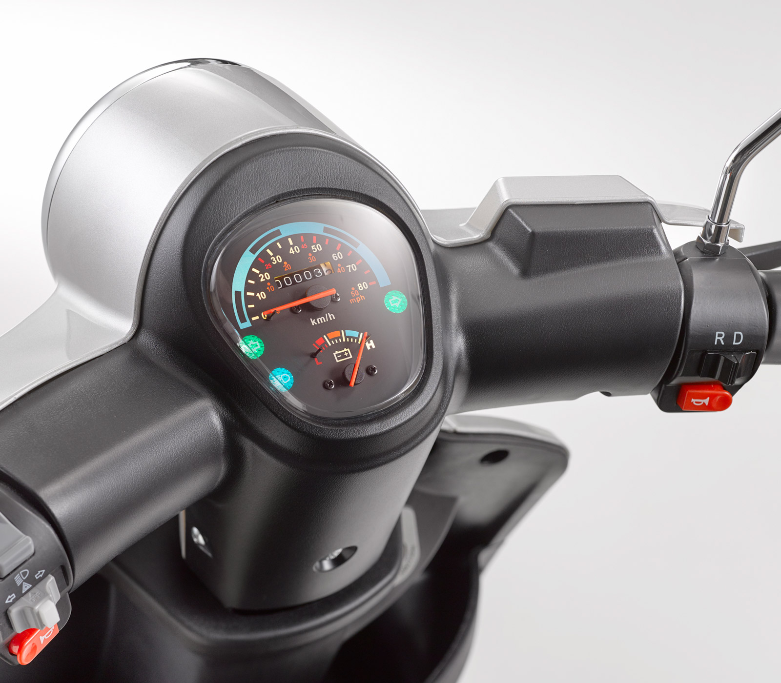 Primo piano del cruscotto di uno scooter con tachimetro, contachilometri e spie luminose.