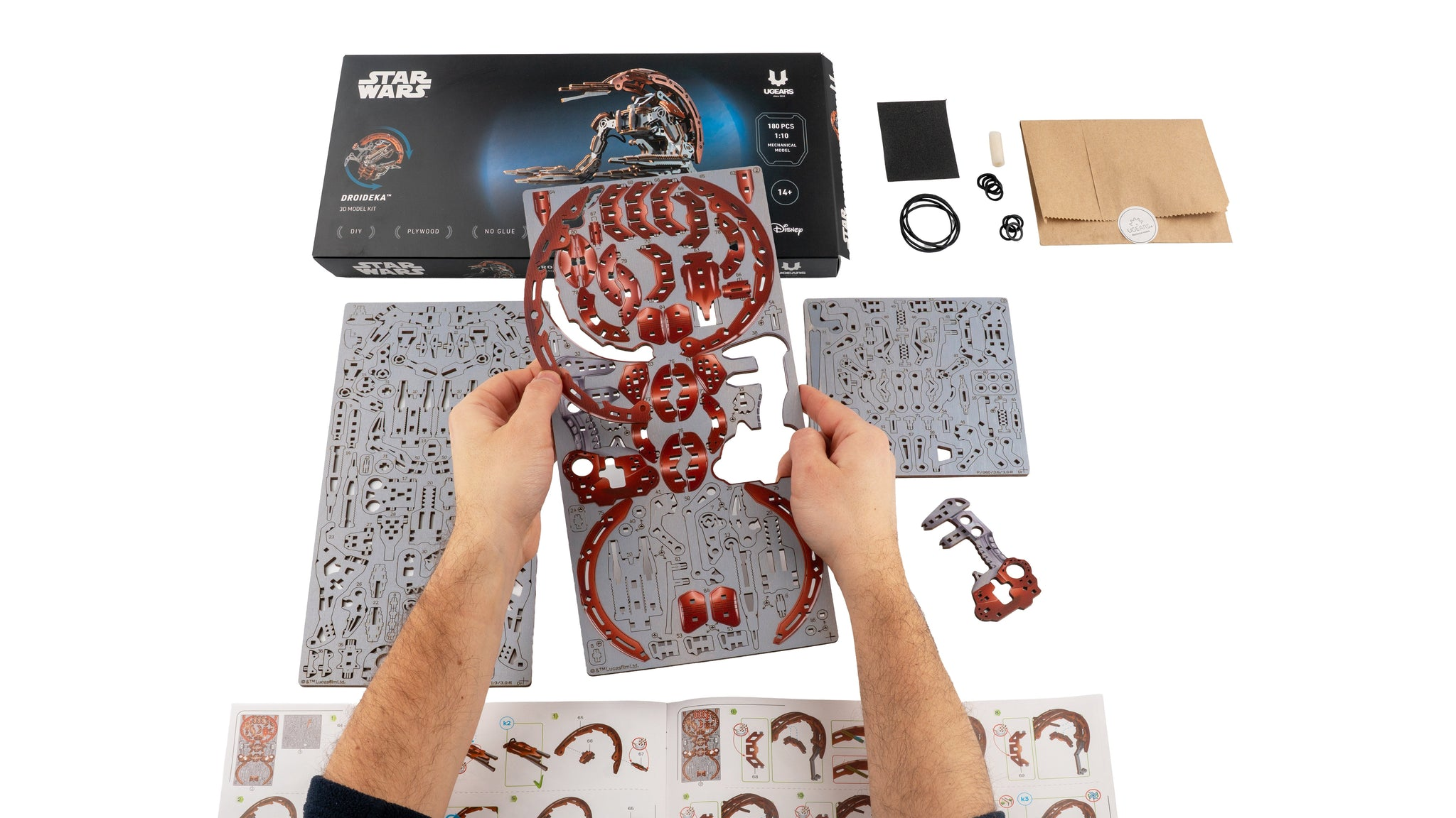 Ein Mann baut ein Star Wars Modellauto-Kit. Enthält Teile, Anleitung und Werkzeuge.