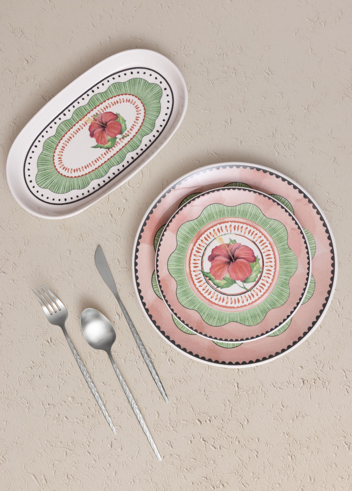 Hibiskus desenli oval servis tabağı ve iki yuvarlak tabak, yanlarında çatal bıçak.