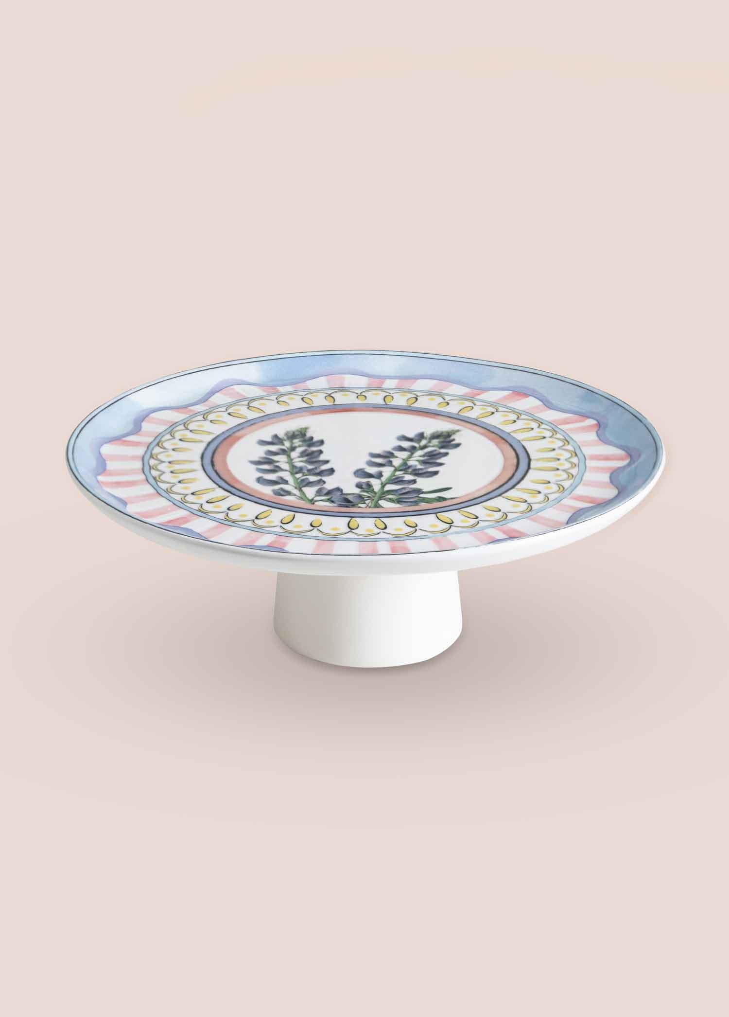 Mavi çiçek desenli ve pembe çizgili beyaz pasta standı.