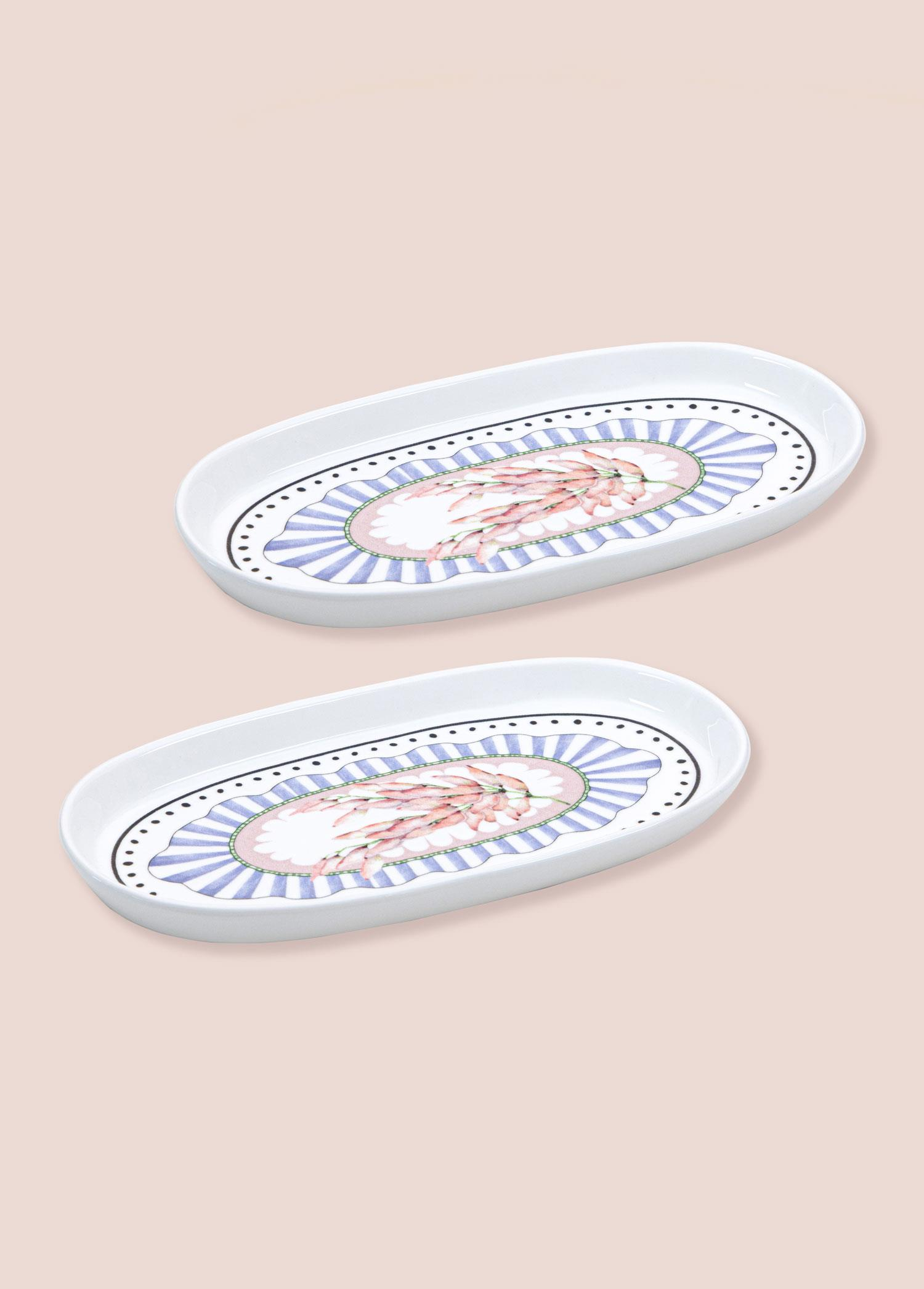 Pembe çiçek desenli ve mavi-beyaz çizgili iki oval beyaz tabak.