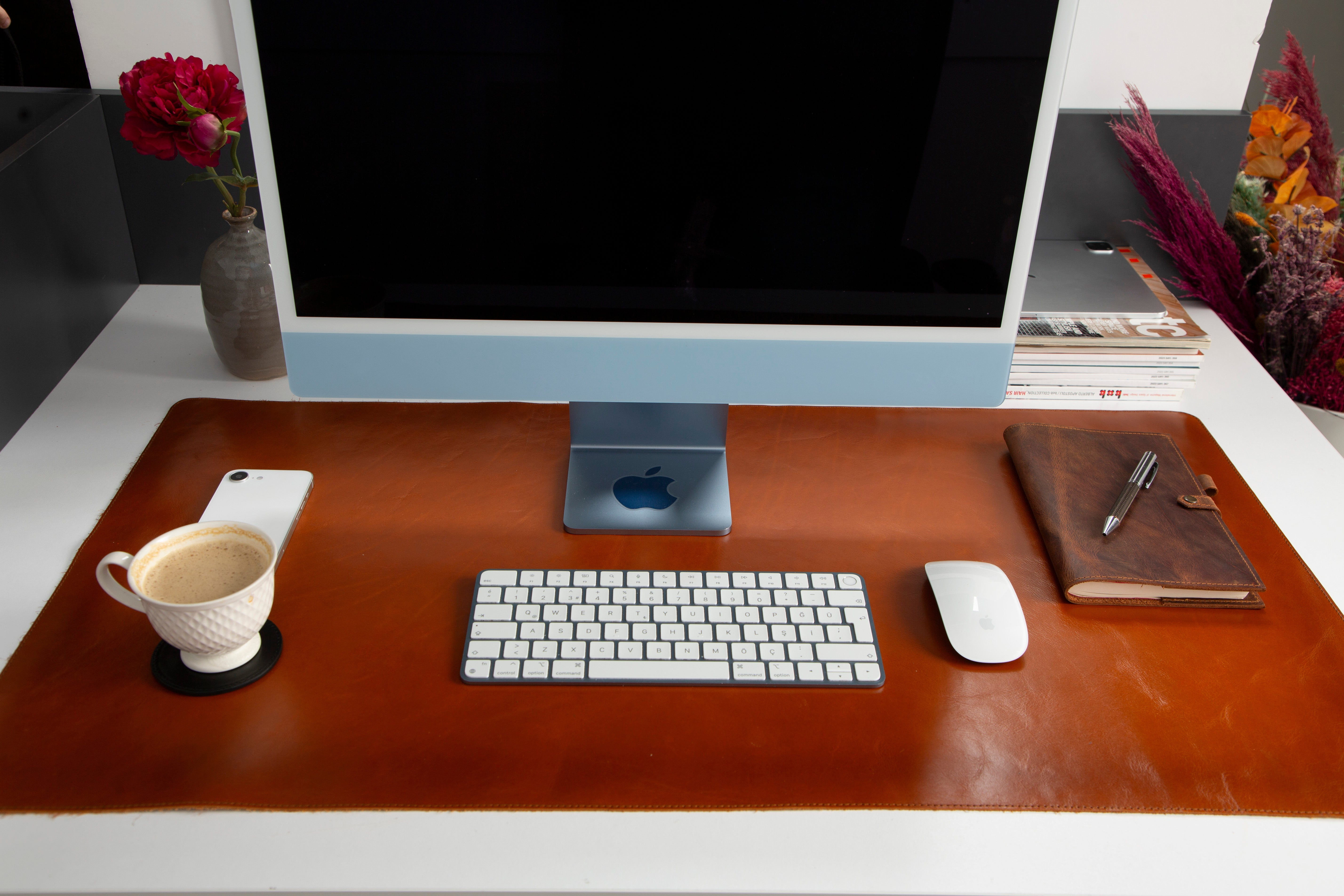 iMac, klavye, fare, kahve ve not defteri olan bir masa.