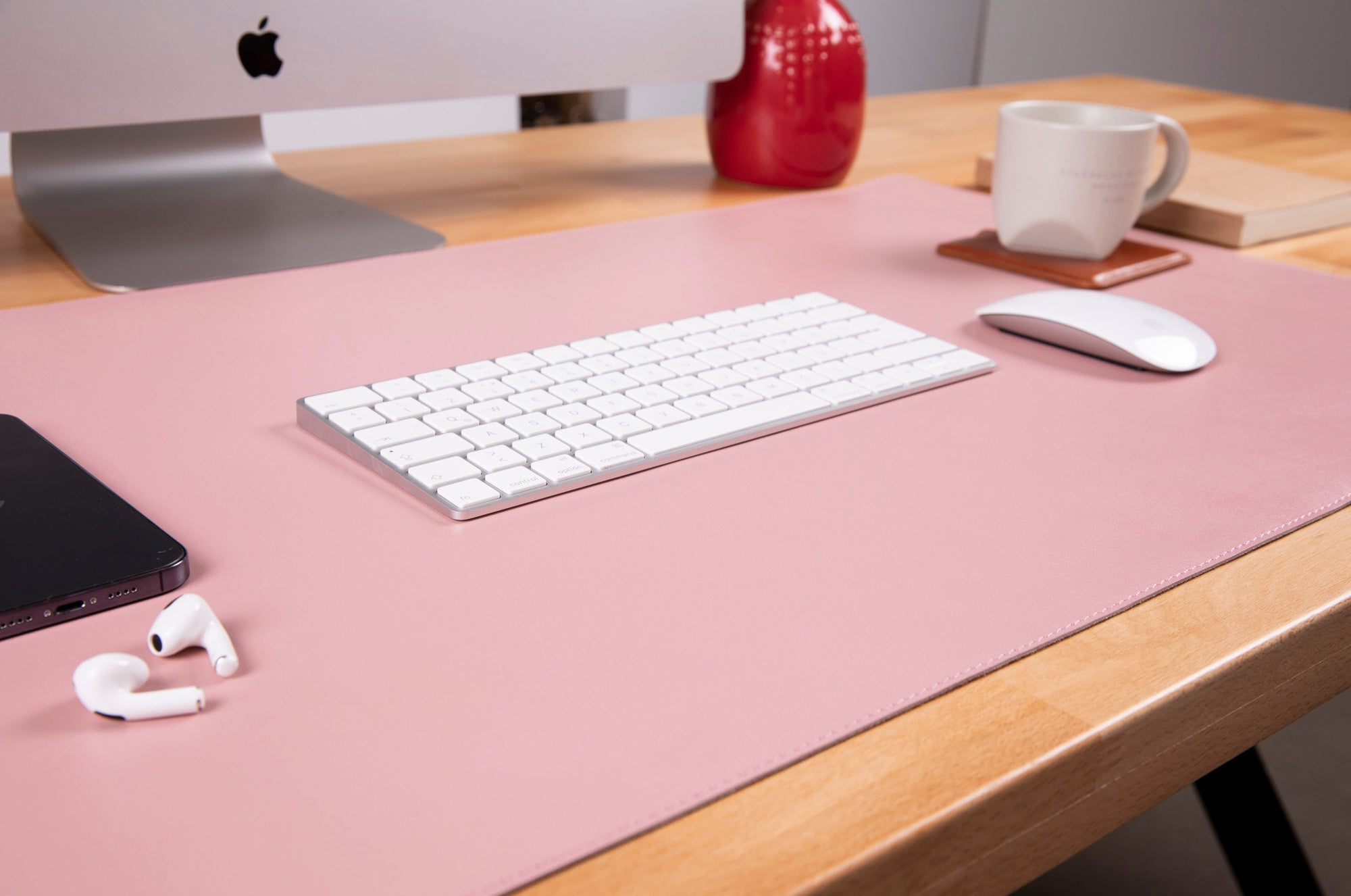 Pembe masa matı üzerinde Apple bilgisayar, klavye, fare, kulaklık ve akıllı telefon.