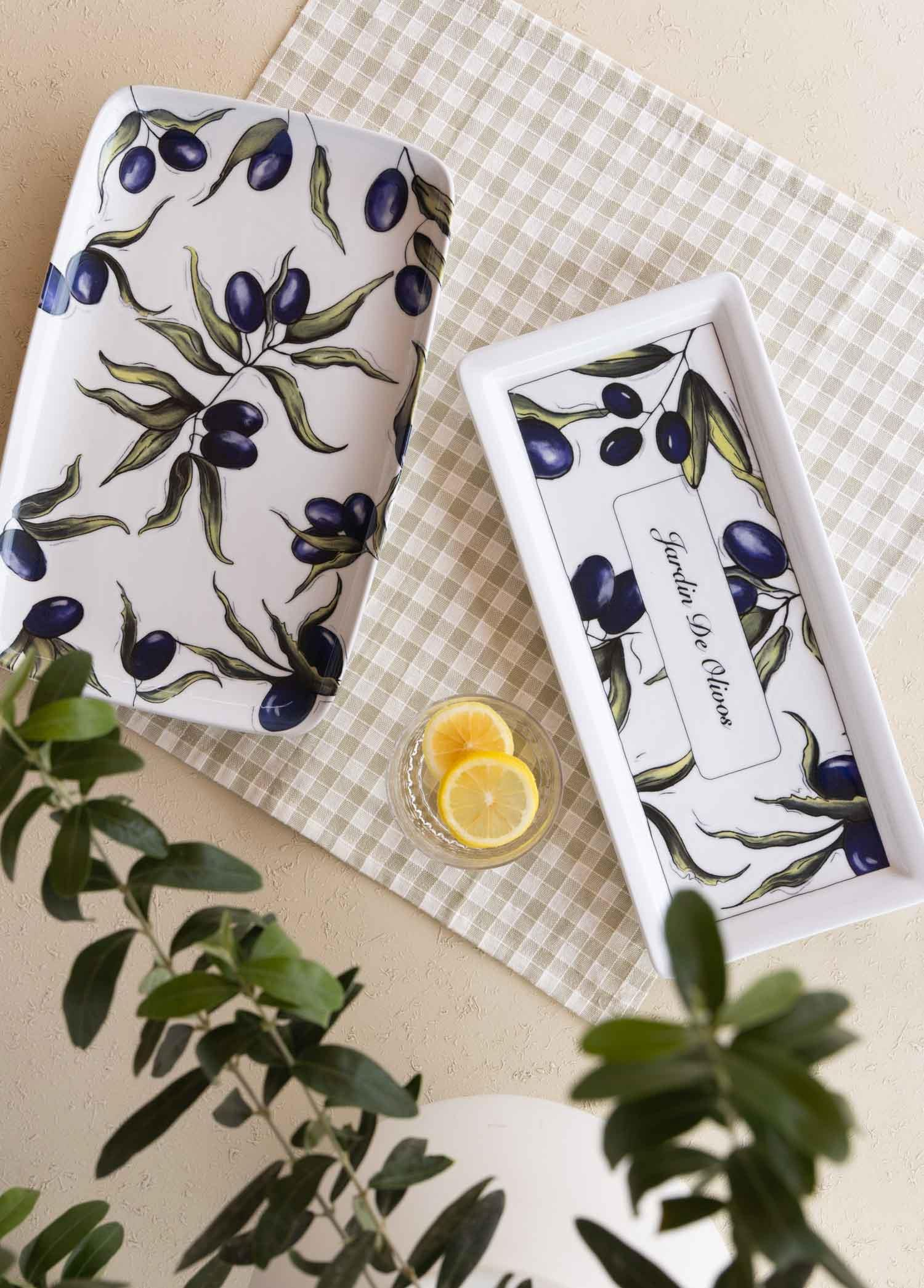 Zeytin dalı desenli iki dikdörtgen beyaz servis tabağı, yanında limon dilimleri.