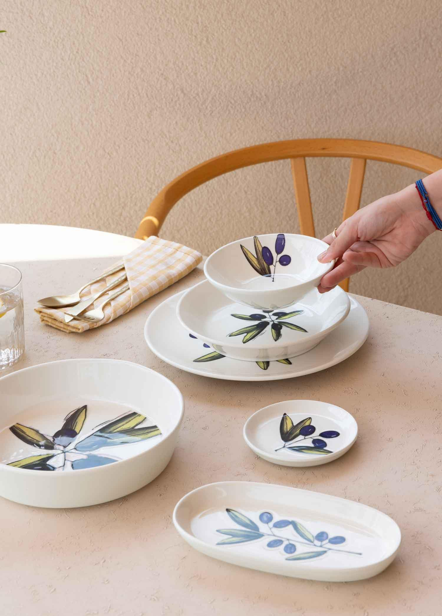 Zeytin dalı desenli beyaz yemek takımı. Kaseler, tabaklar ve çatal bıçak içerir.