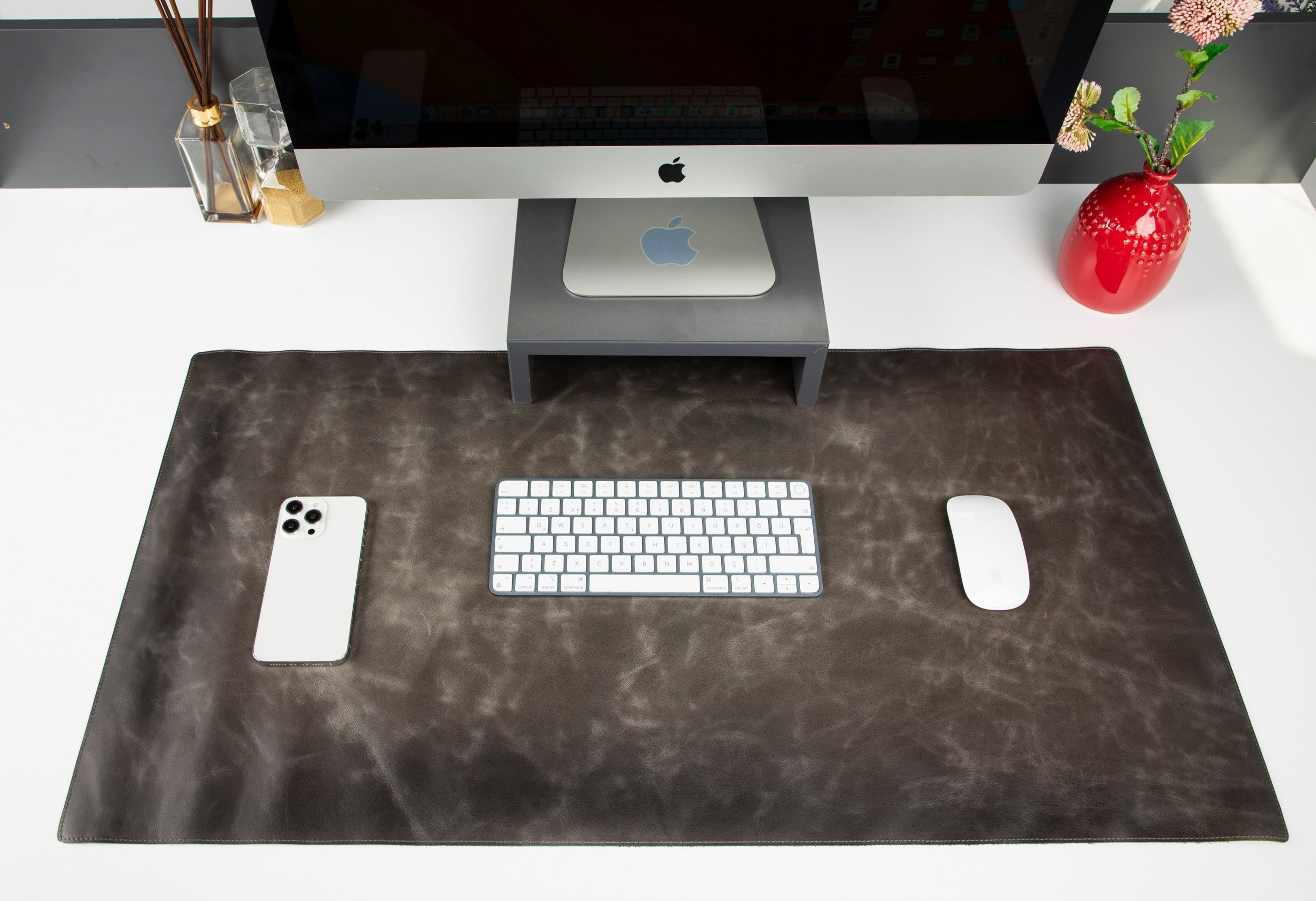 Bir iMac, klavye, fare, akıllı telefon ve difüzör masaya serilen bir örtü üzerinde.