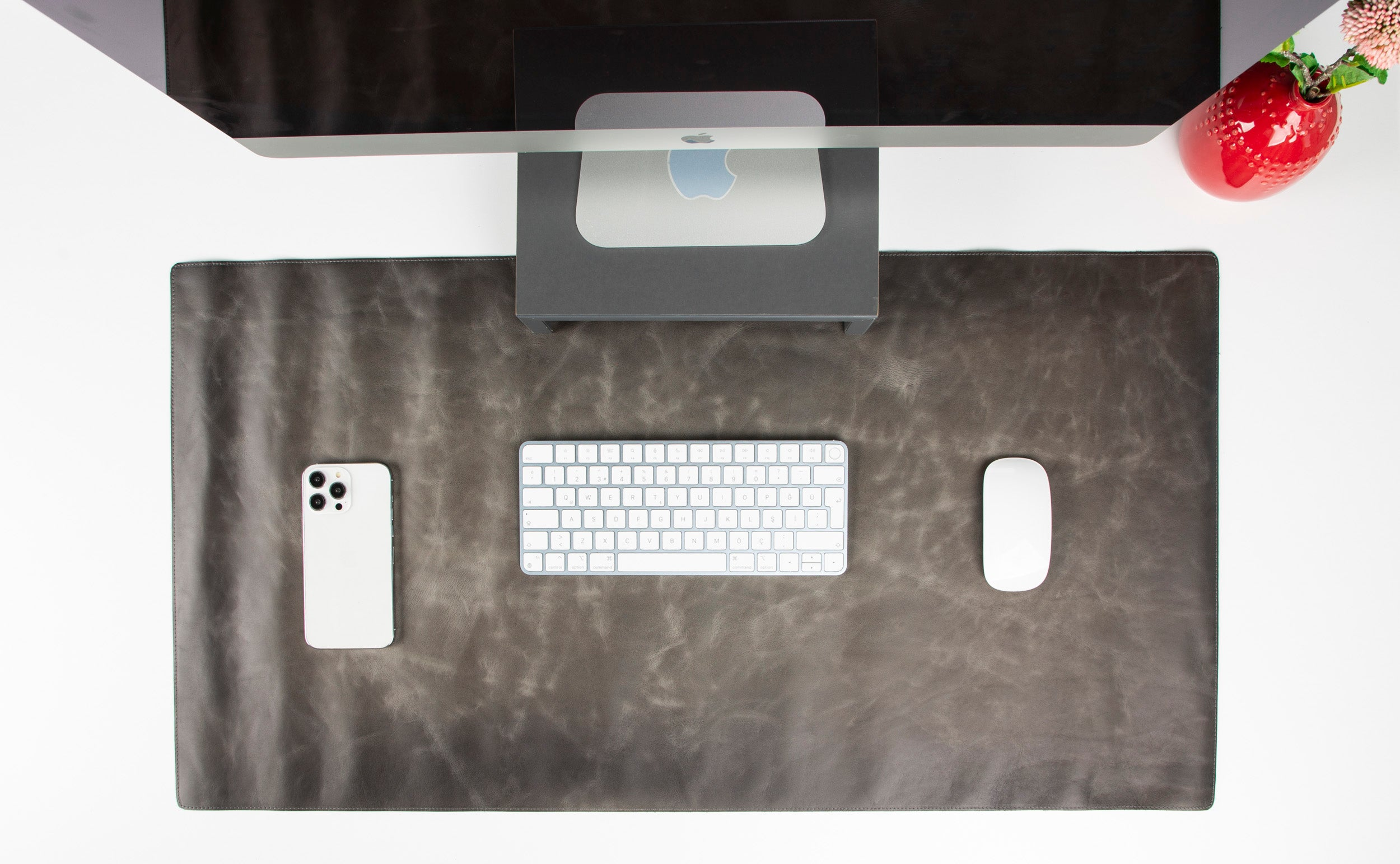 Kahverengi mat üzerinde beyaz bir akıllı telefon, klavye ve fare.