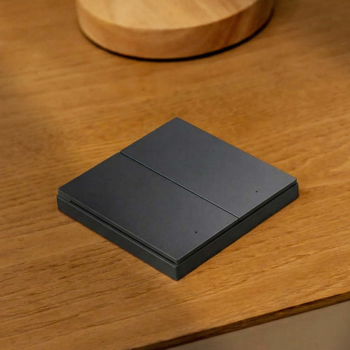 Un interrupteur noir à deux boutons sur une table en bois.