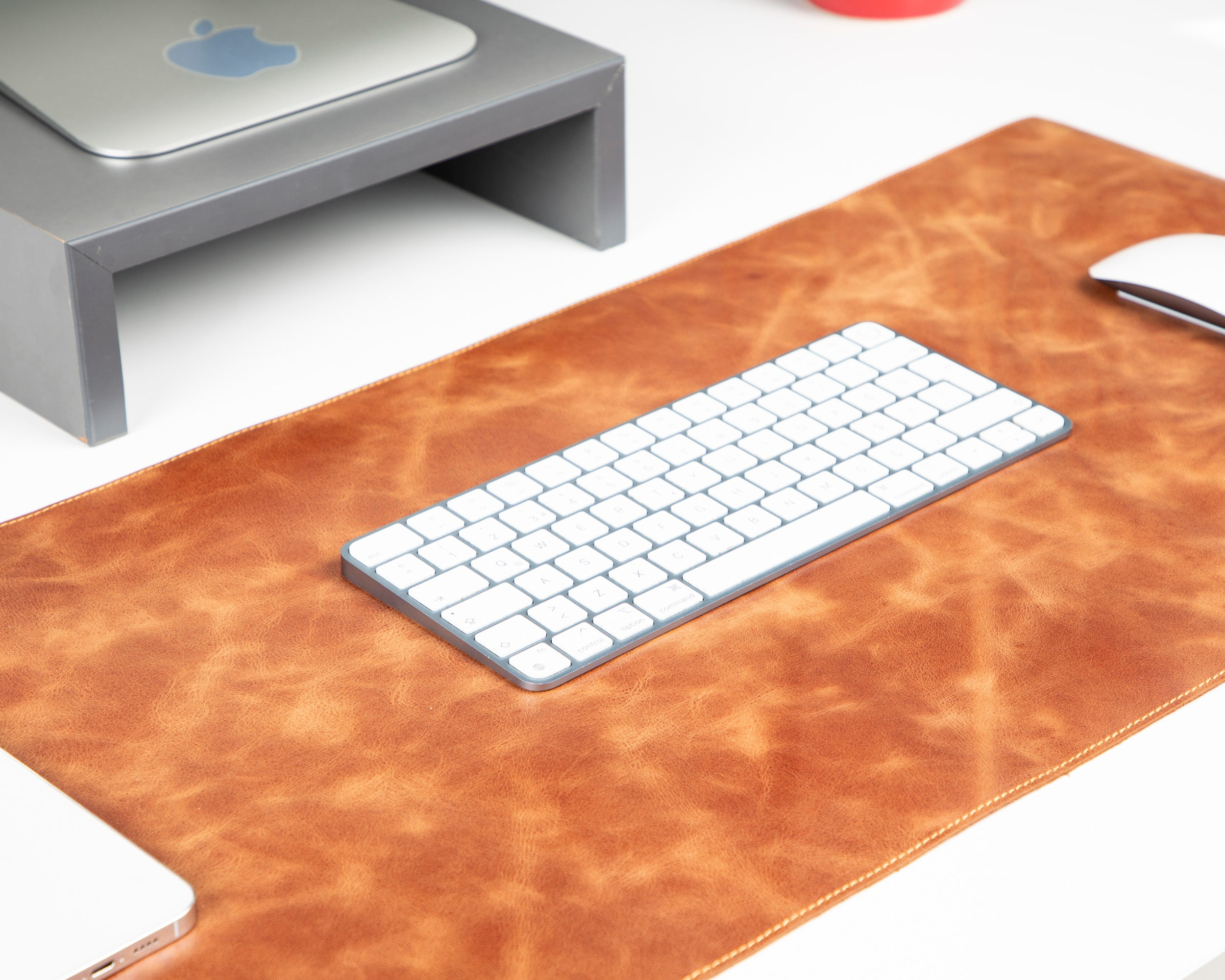 Kahverengi deri masa matı üzerinde beyaz bir Apple Magic klavye.