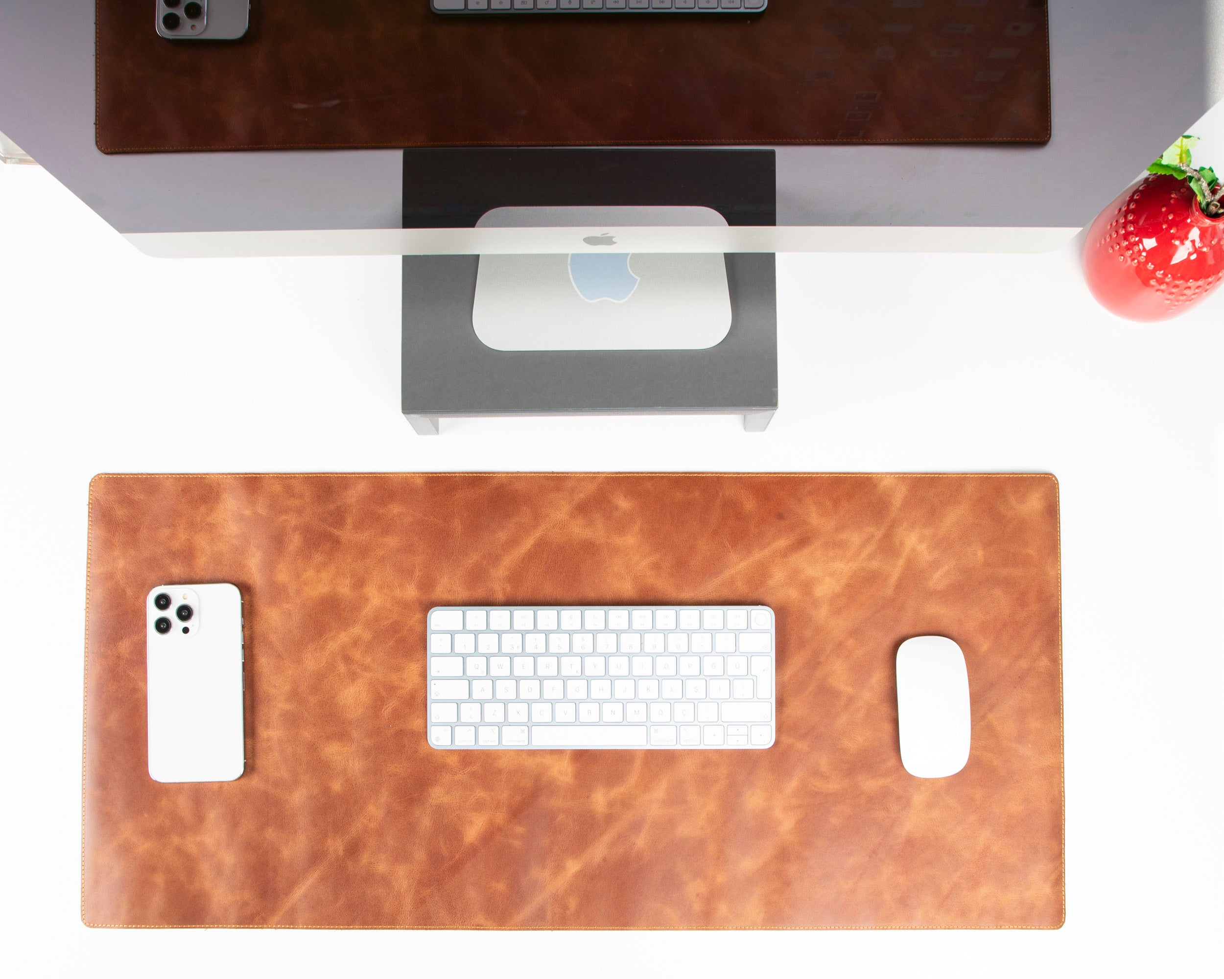 Apple iMac, klavye, fare, telefon ve kırmızı dekorasyonlu bir masa.