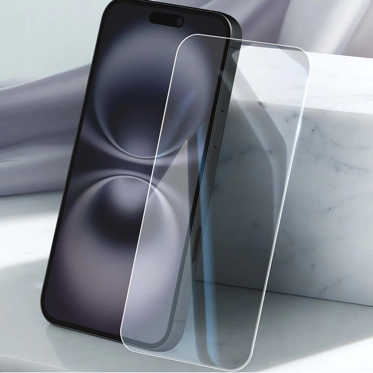 Uno smartphone scuro con una protezione per lo schermo accanto, su marmo.
