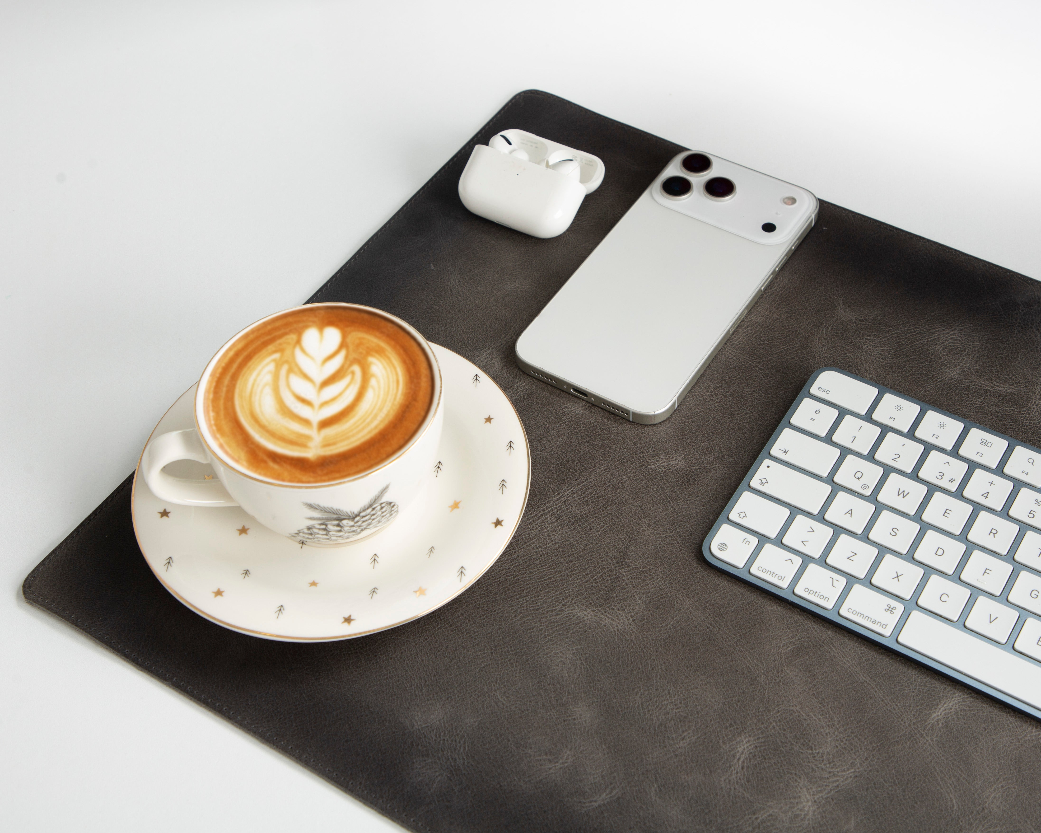 Latte art'lı kahve fincanı, yanında akıllı telefon, kulaklık ve klavye.