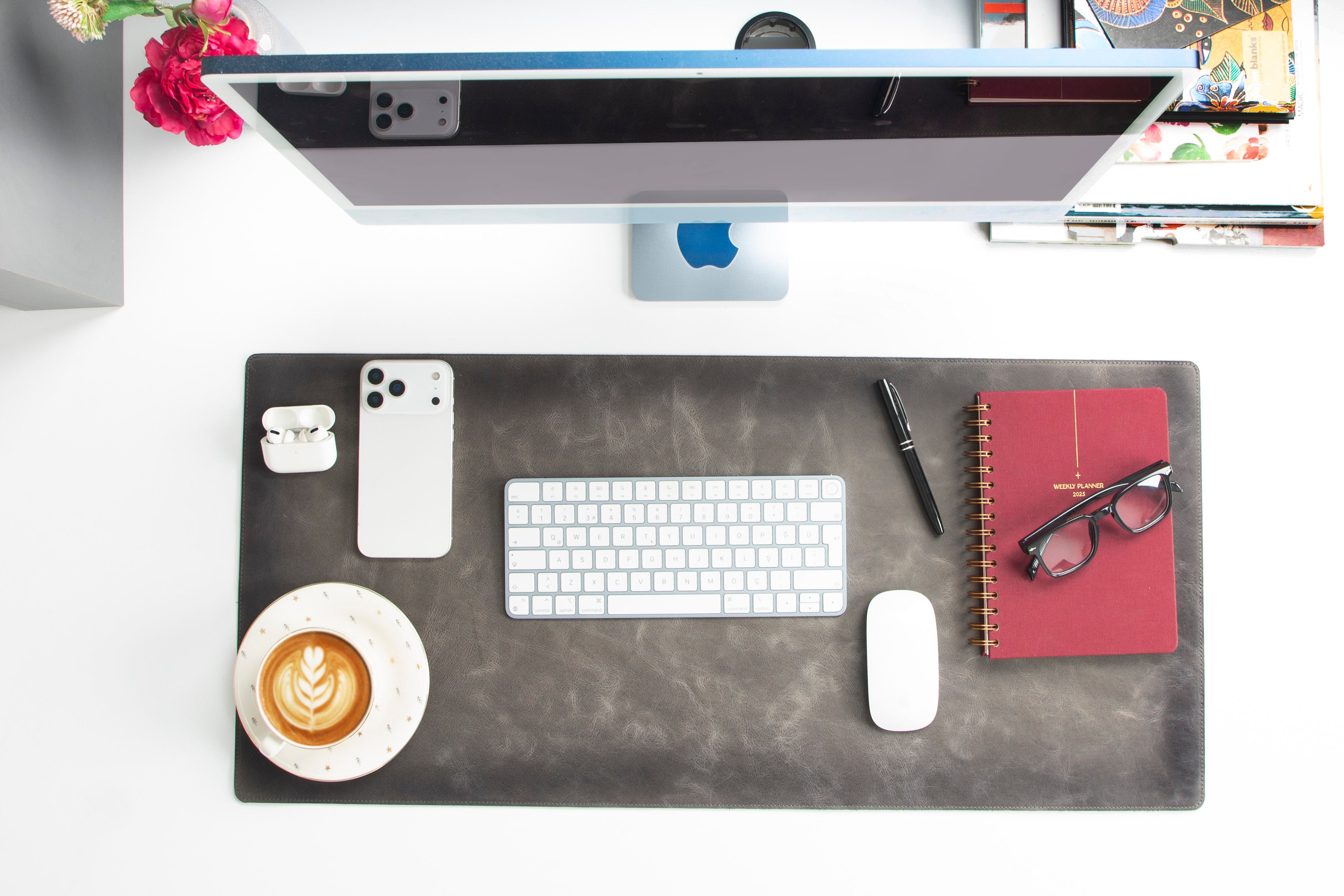 iMac, klavye, fare, telefon, kulaklık, kahve ve planlayıcı içeren masaüstü düzeni.