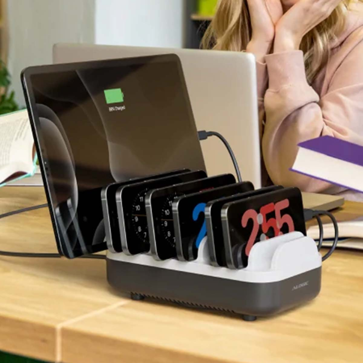 Ein Ladeständer mit mehreren Telefonen, einem Tablet und einem Laptop auf einem Schreibtisch.