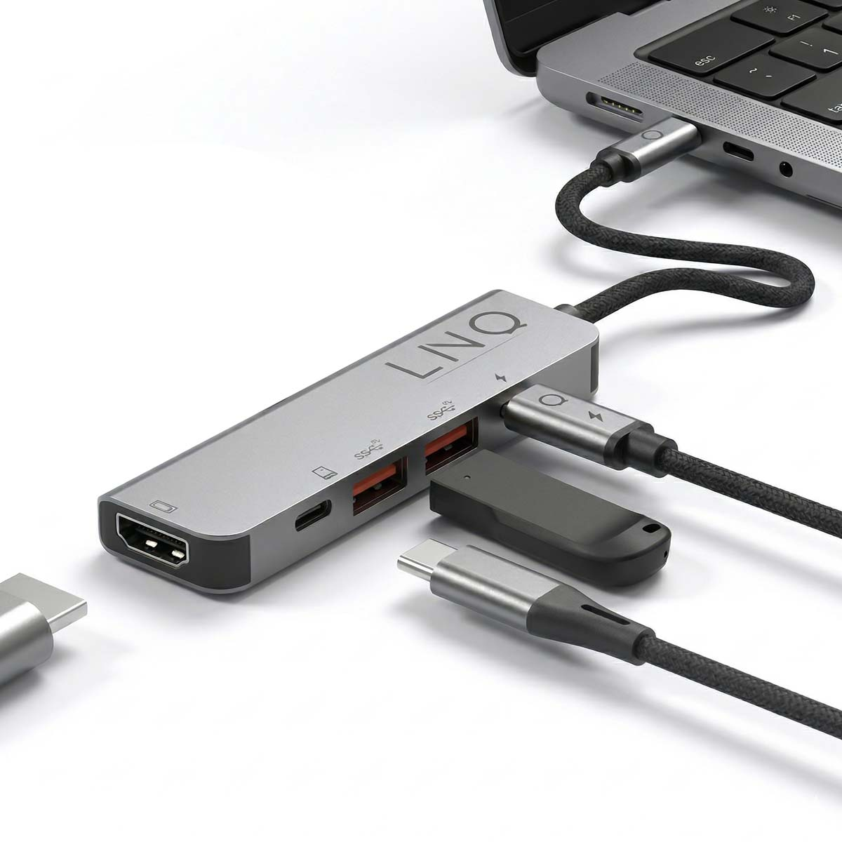 Un hub USB-C argento è collegato a un laptop. Diversi cavi e dispositivi sono collegati.