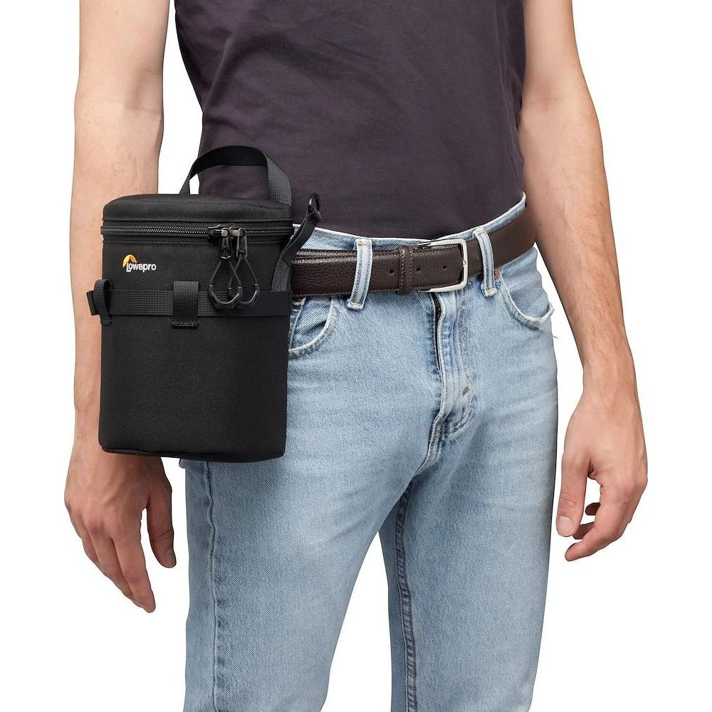 Eine schwarze Lowepro Kameratasche hängt an einem braunen Ledergürtel, der von einer Person in Jeans getragen wird.