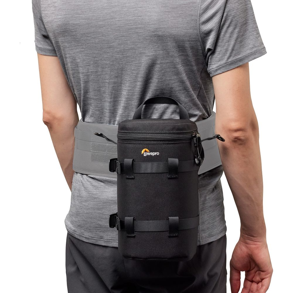 Eine schwarze Lowepro-Objektivtasche mit Riemen ist an einem grauen Gürtel an einer Person befestigt.