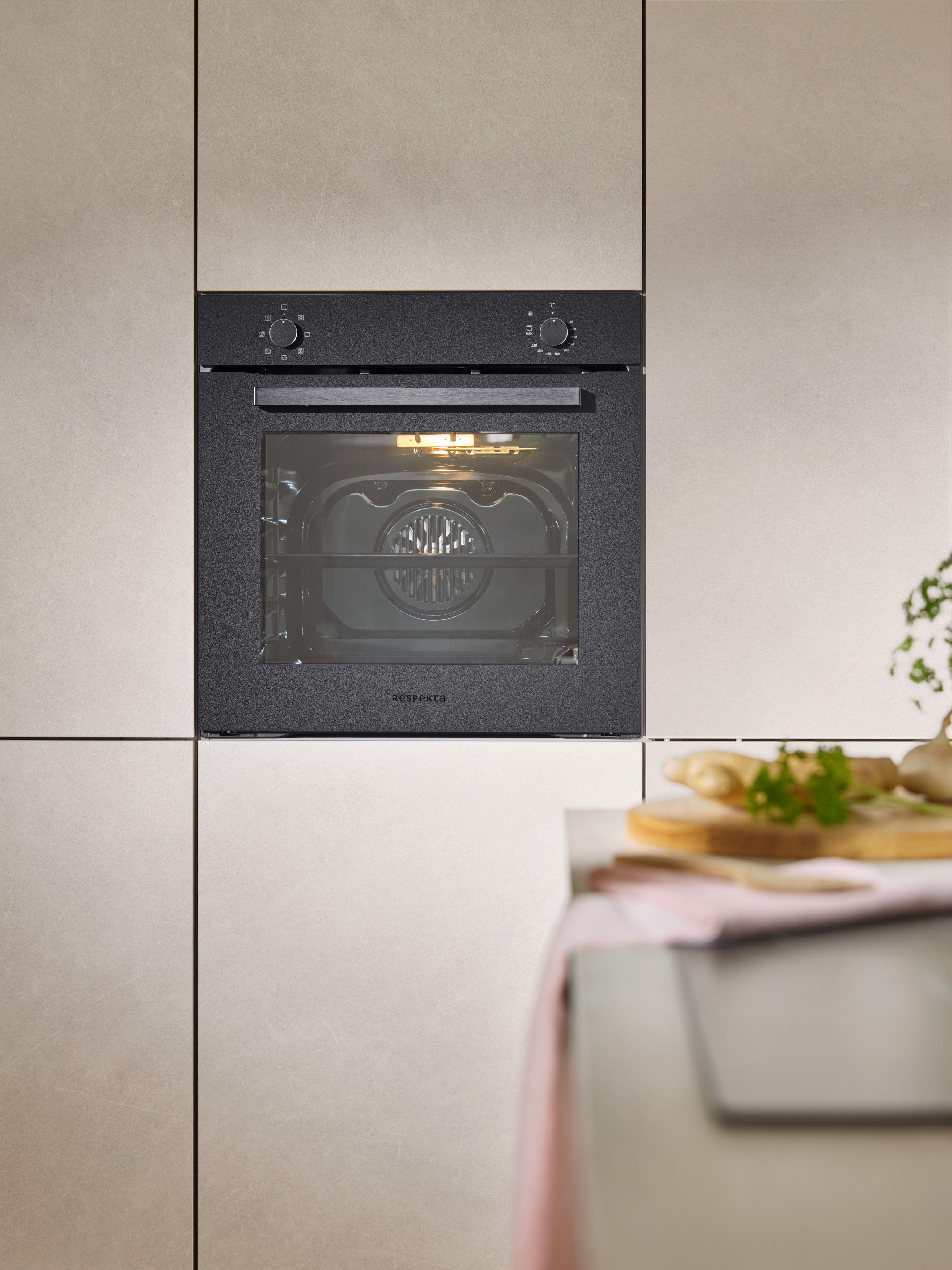Een donkere inbouwoven met glazen deur in een moderne keuken. Binnen brandt het licht.