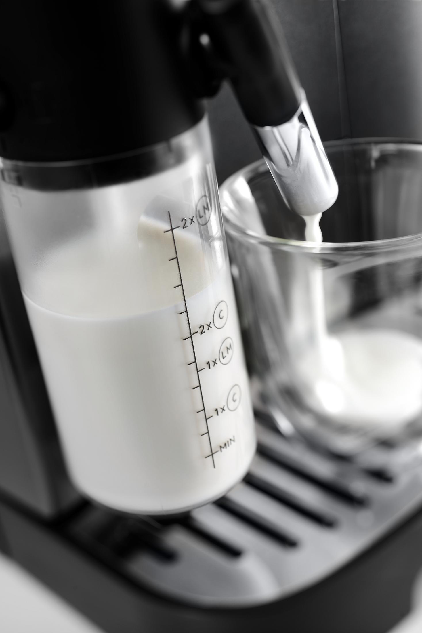 Il latte viene versato da un contenitore graduato in un bicchiere, una macchina da caffè.