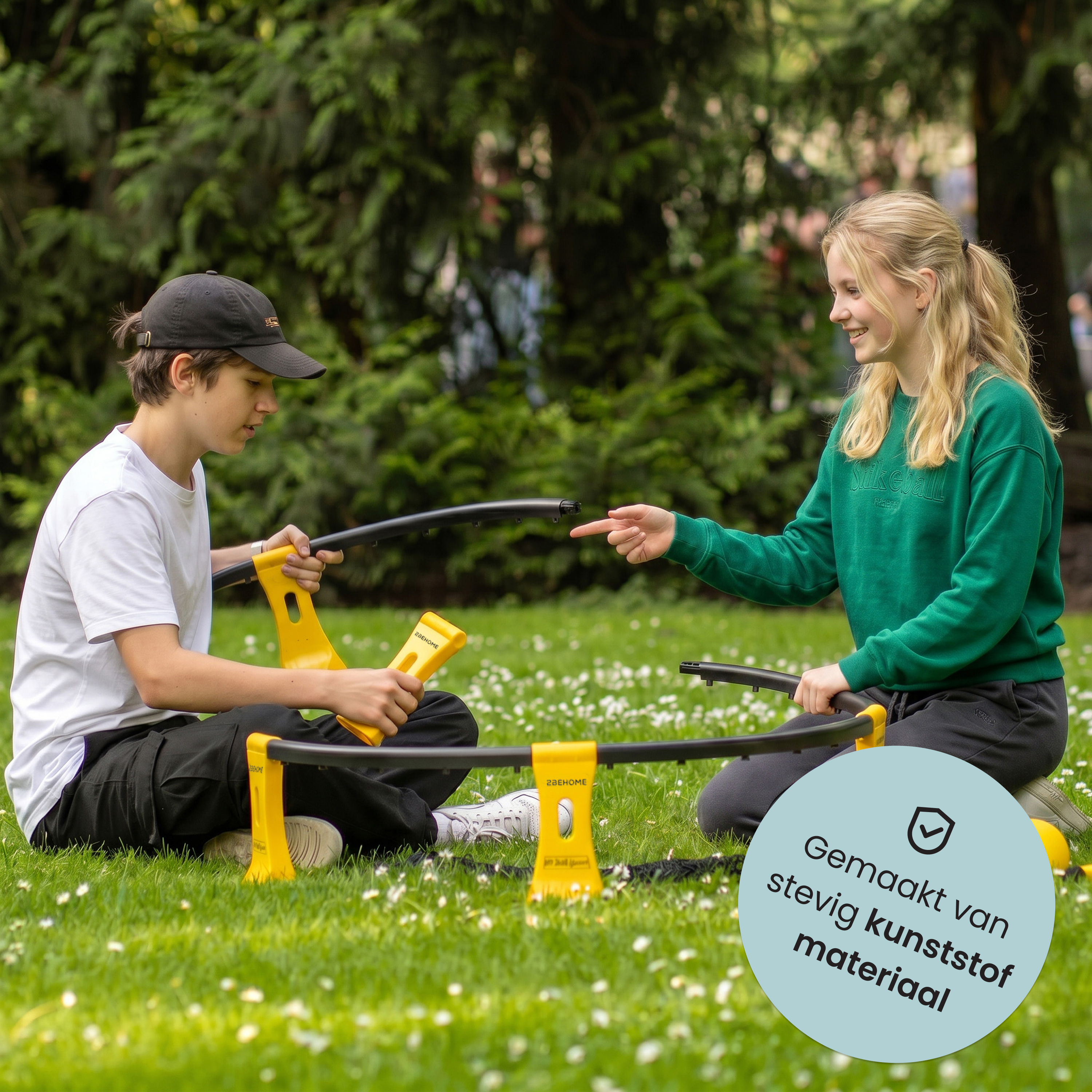 Zwei Kinder bauen im Gras ein Spielzeug. Ein Junge mit Kappe und ein Mädchen im grünen Pullover.