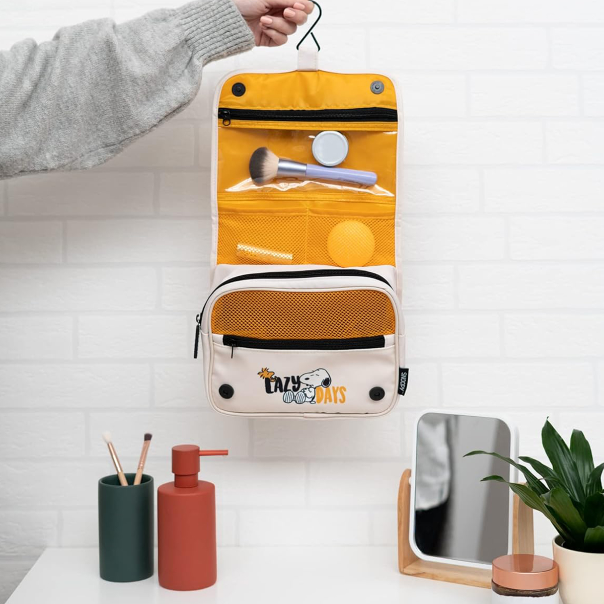 Hängende Kulturtasche mit Snoopy-Motiv, Make-up-Pinsel und Kompaktpuder.