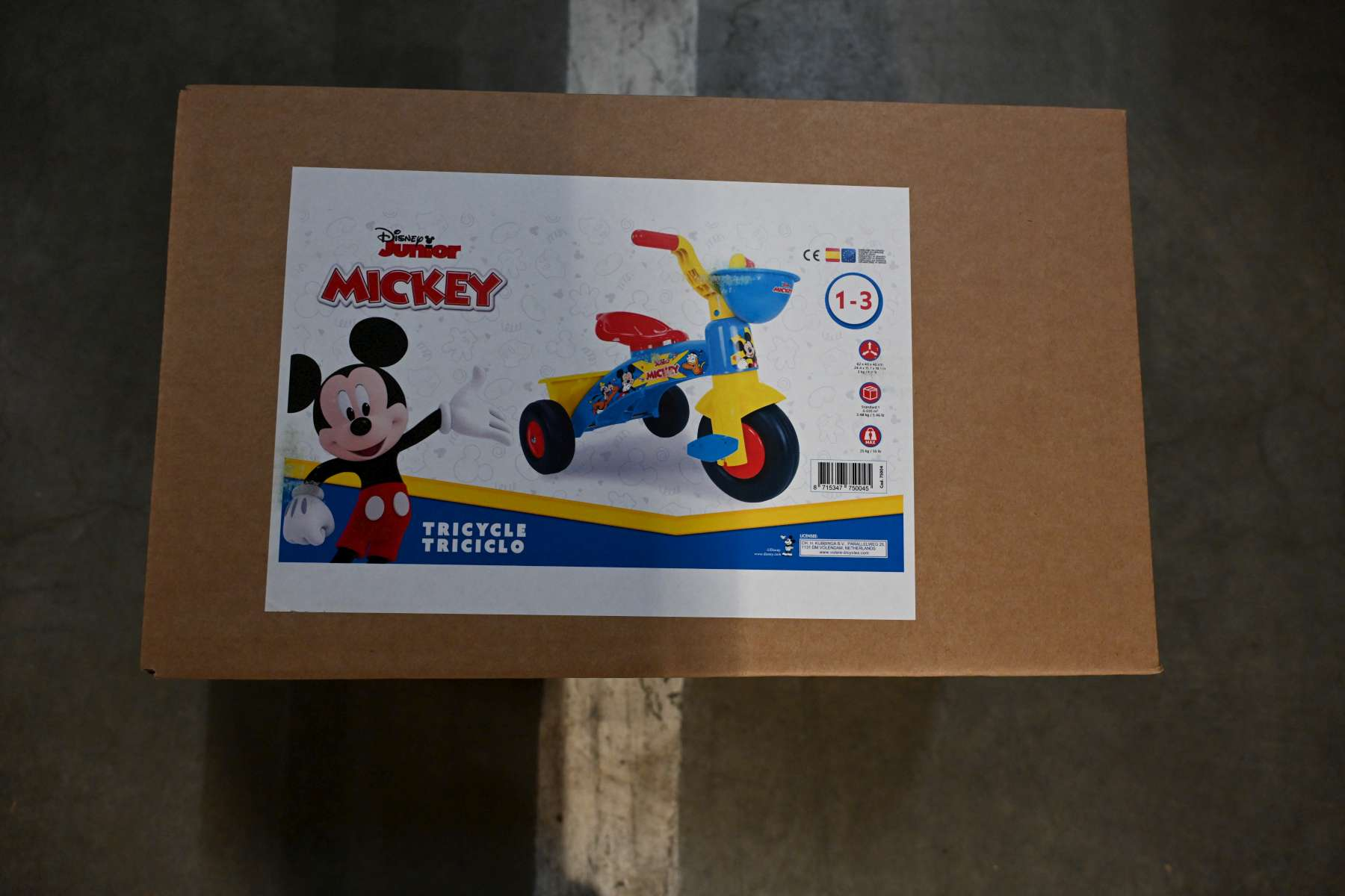 Ein bunter Kinderdreiradkarton mit Micky Maus und einem Dreirad.