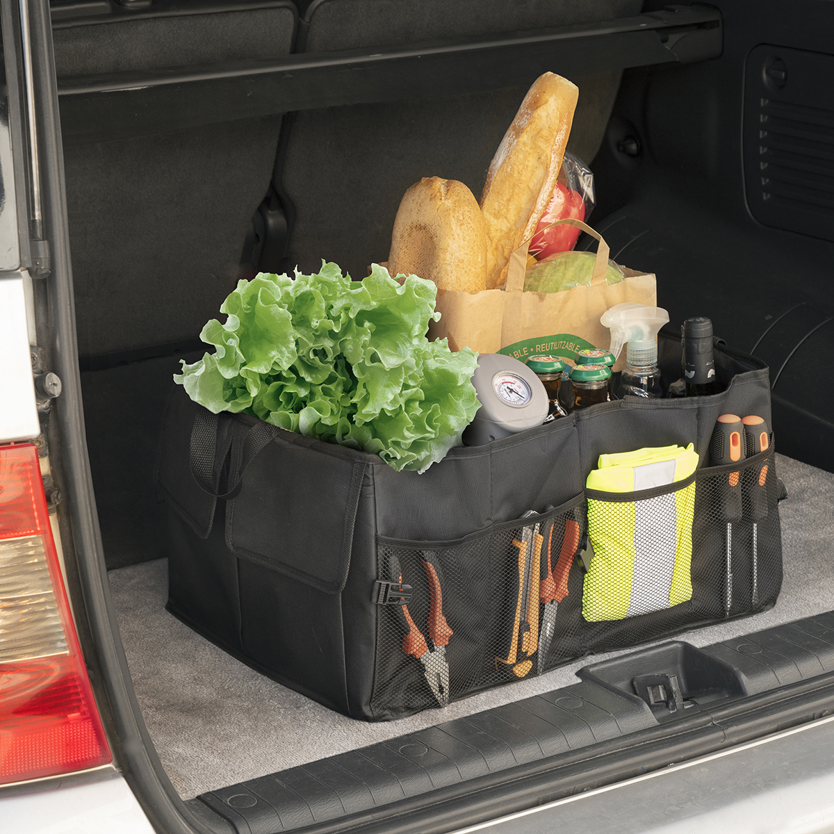 Kofferraum-Organizer mit Lebensmitteln, Brot und Werkzeugen. Salat, Baguettes, Gläser, Sprühflasche, Reifendruckprüfer.