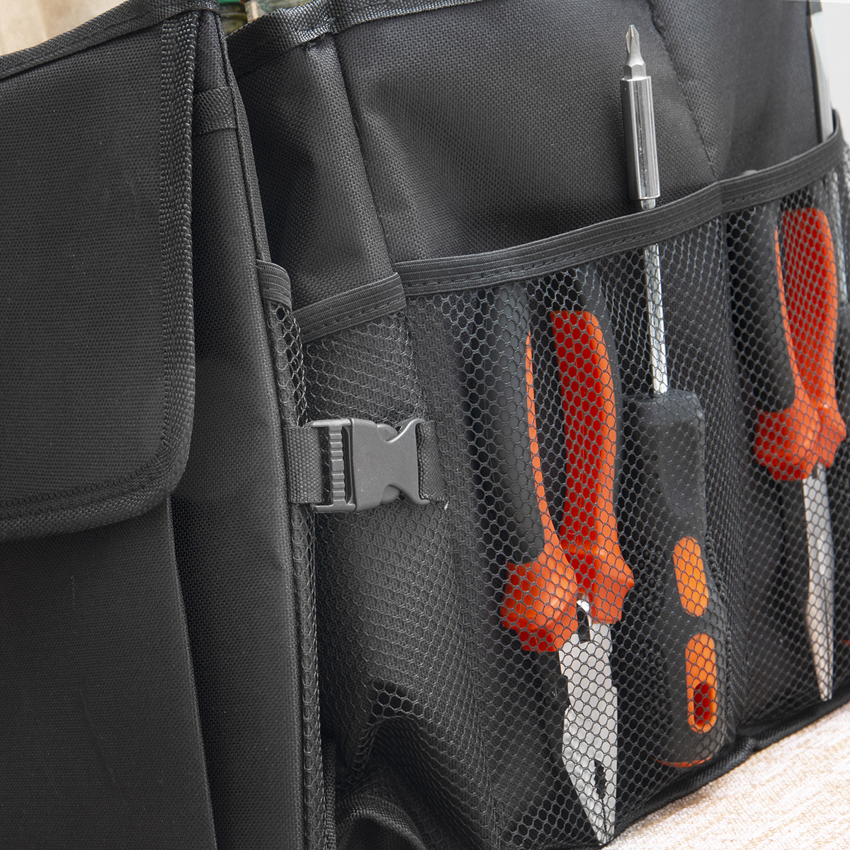 Schwarze Werkzeugtasche mit Netzfächern, darin Schraubendreher mit orangen Griffen.