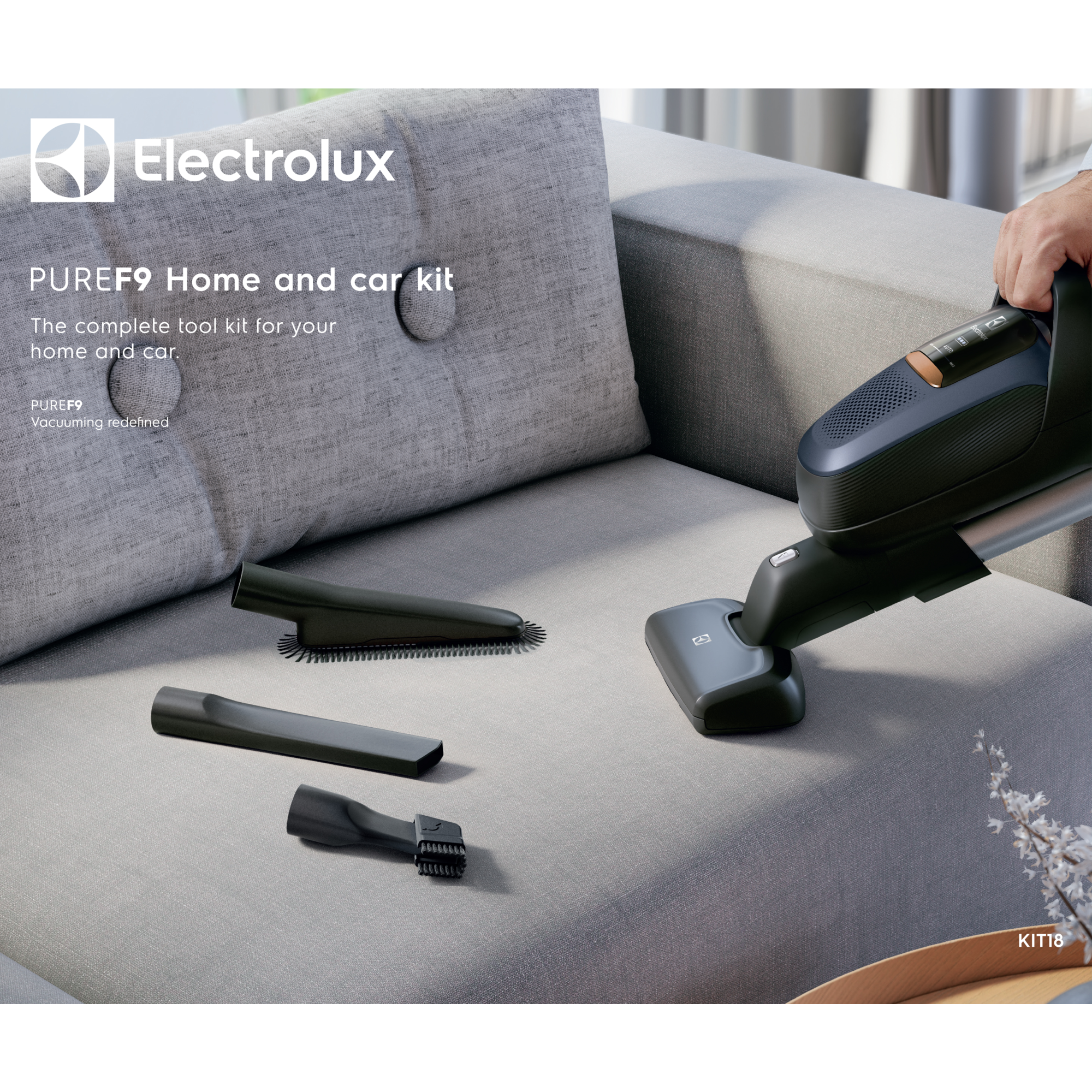 Una aspiradora de mano con accesorios sobre un sofá, logo Electrolux.