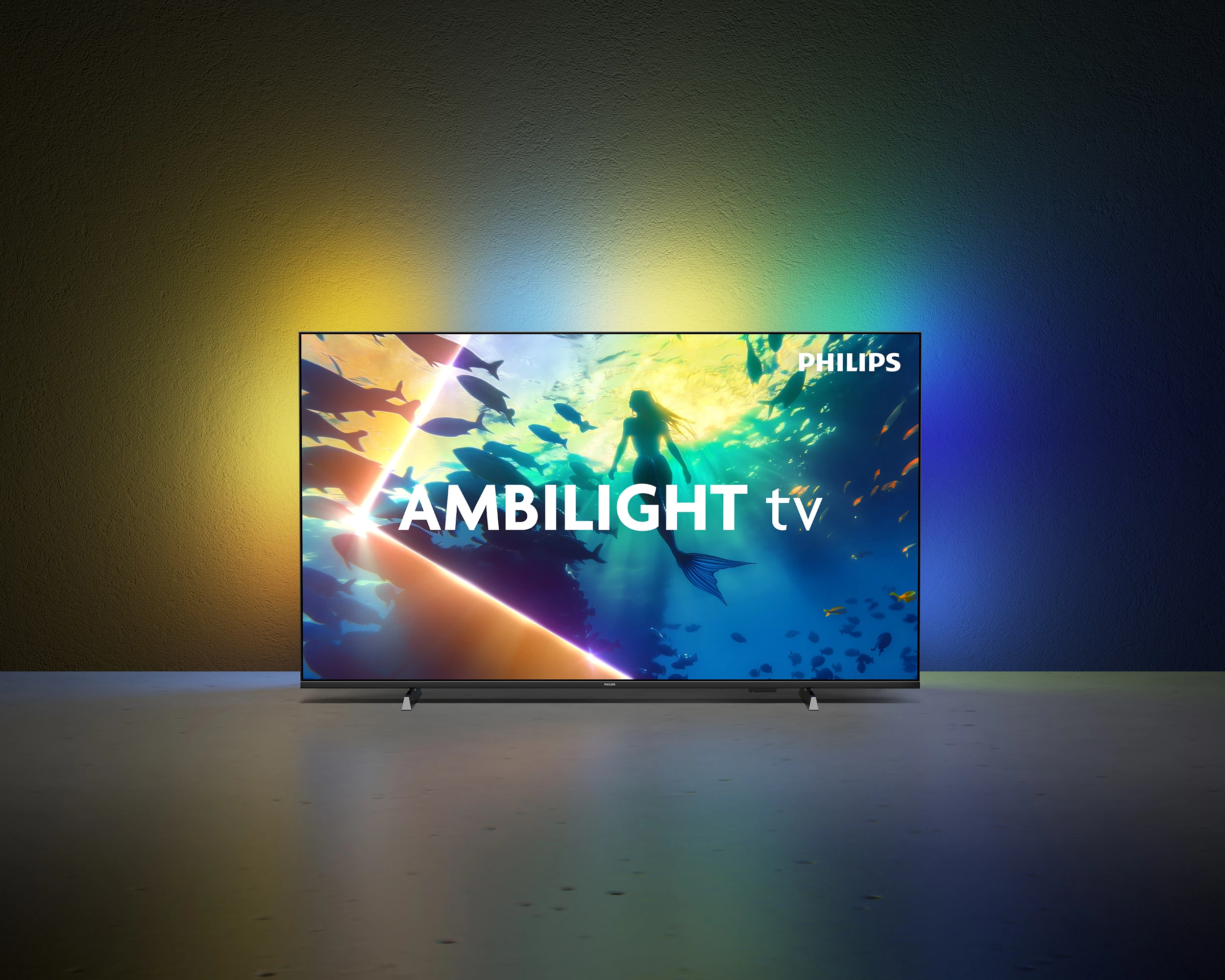Telewizor Philips Ambilight pokazuje syrenę i ryby pod wodą. Emanuje żółte i niebieskie światło.