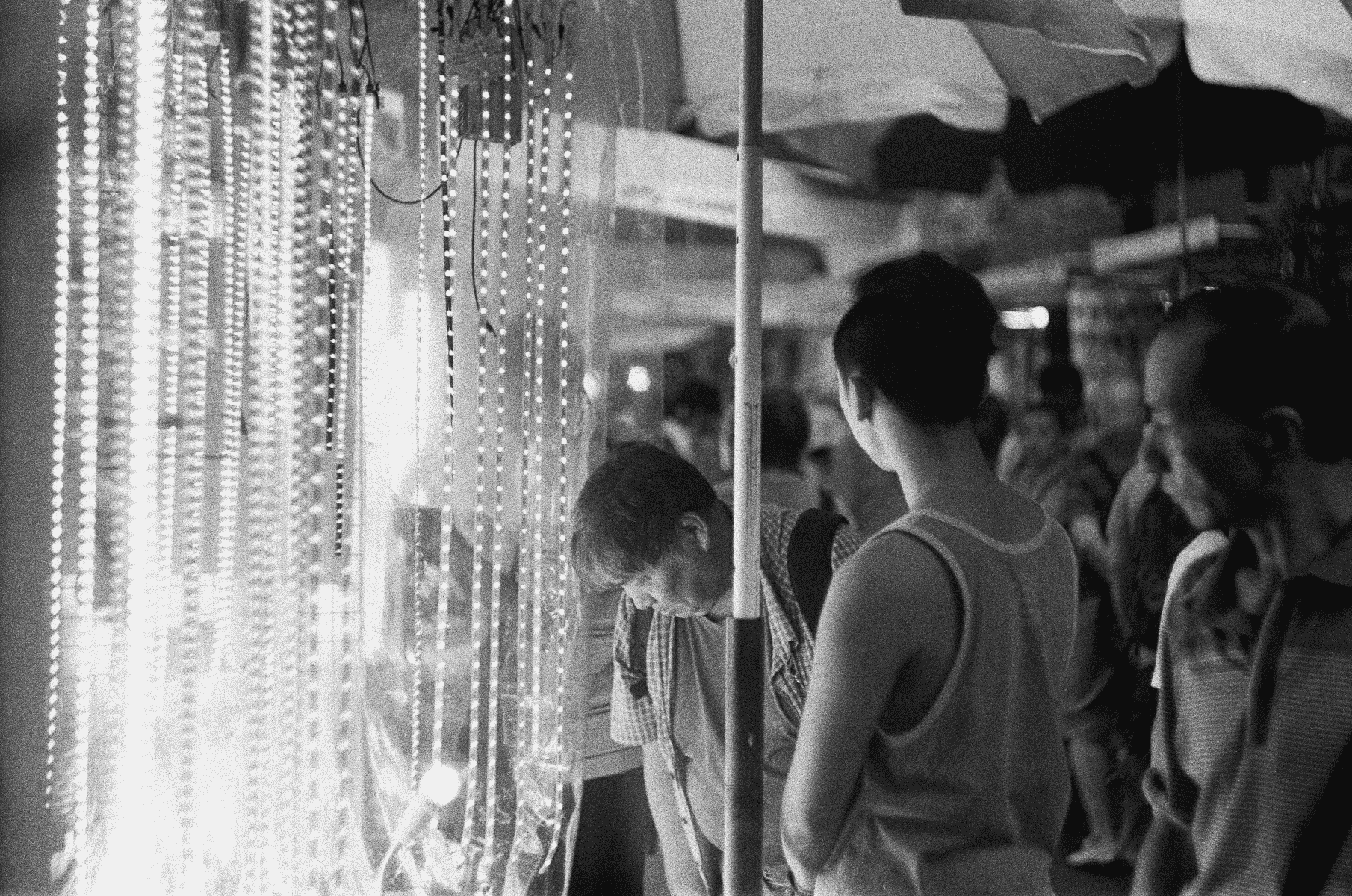Gente mirando luces de cadena en un mercado.