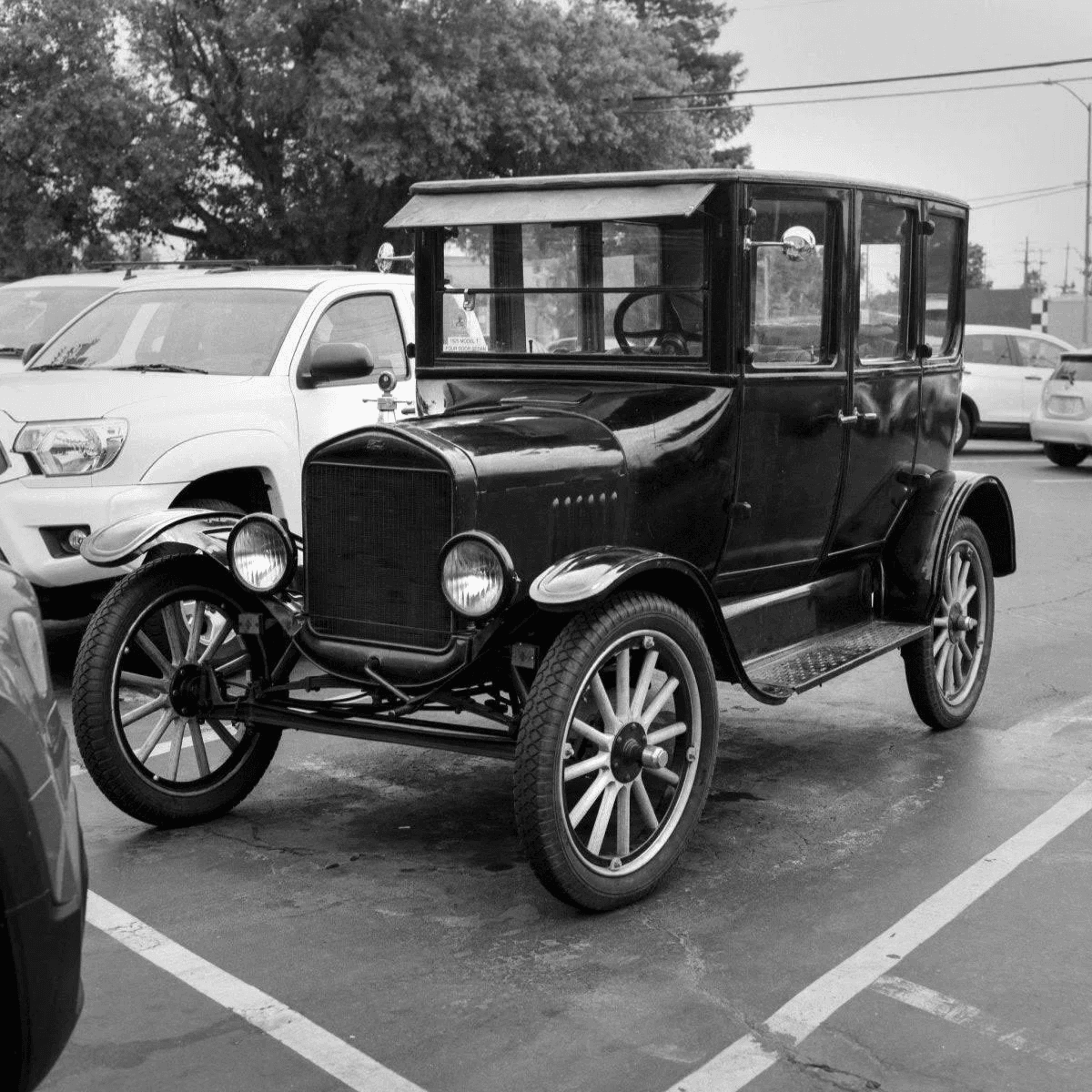 Un coche antiguo negro con ruedas de radios de madera está aparcado.