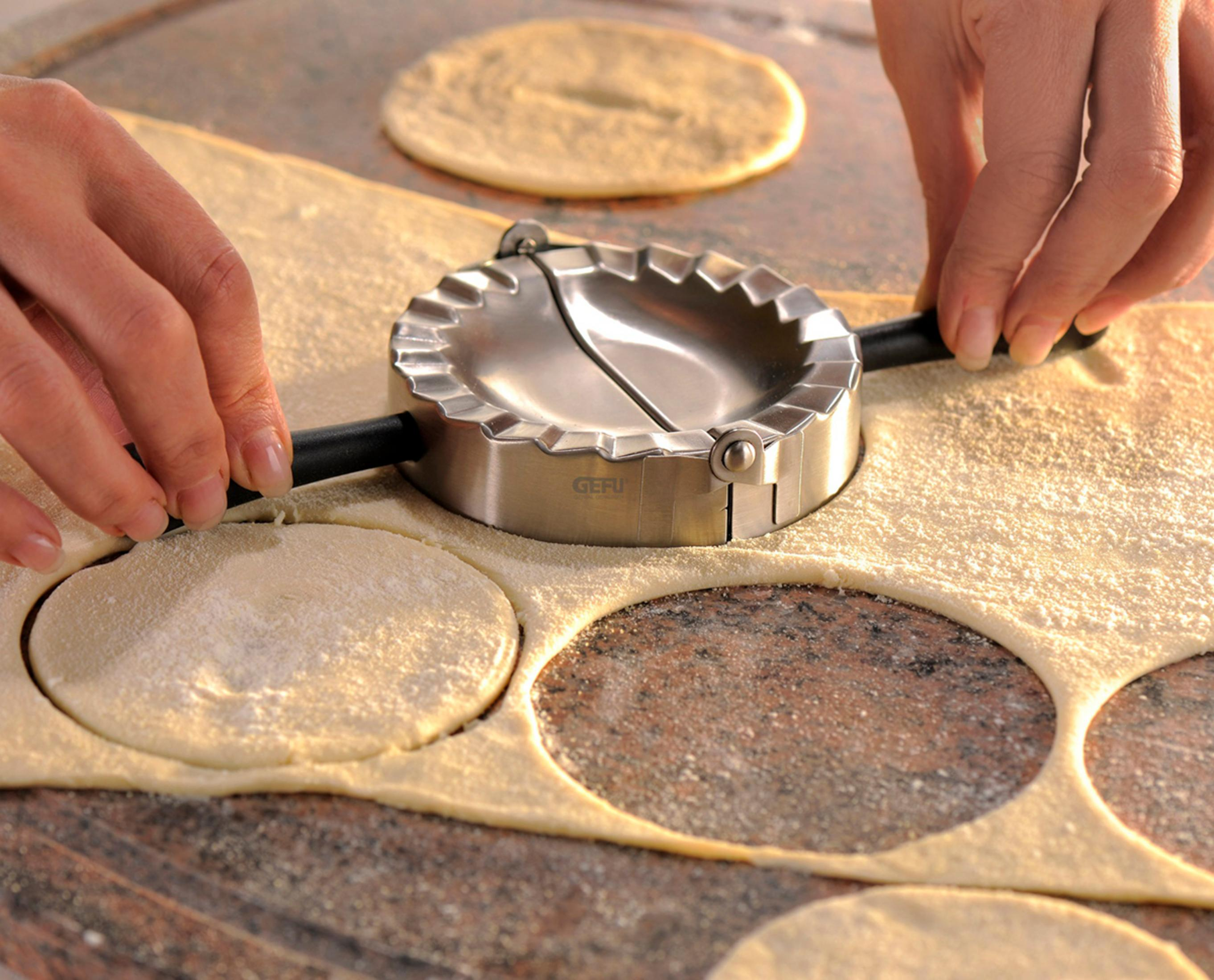 Des mains utilisent un emporte-pâte pour découper des cercles dans la pâte.