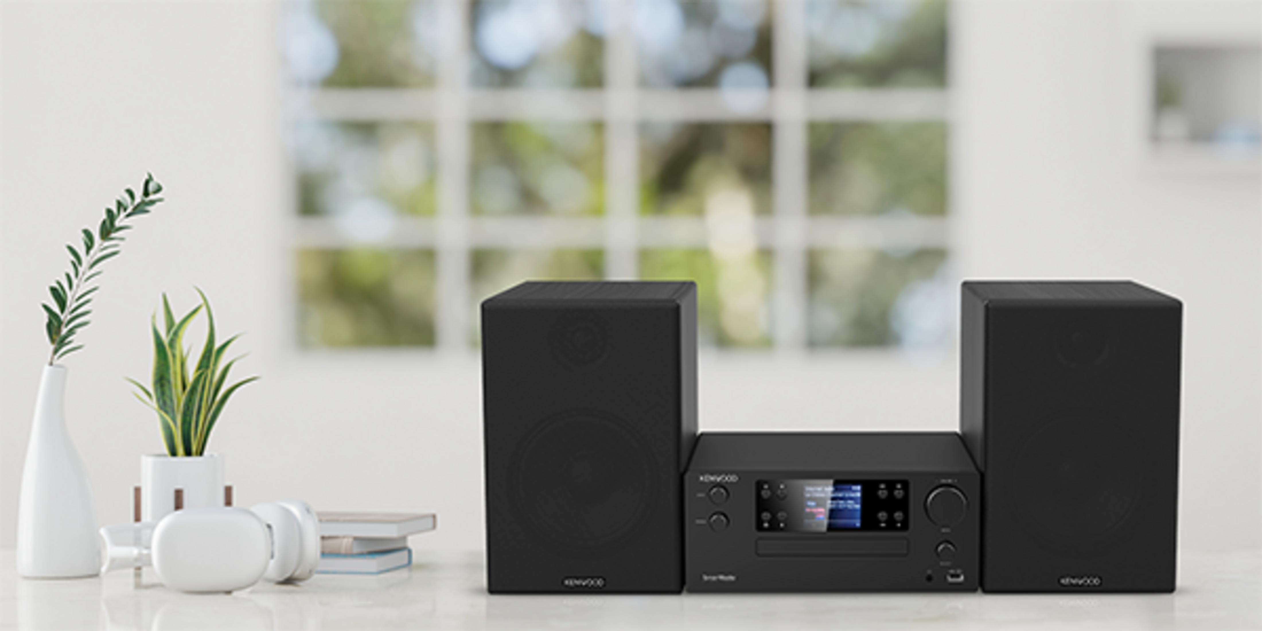 Un sistema stereo Kenwood nero con due altoparlanti è appoggiato su un tavolo.