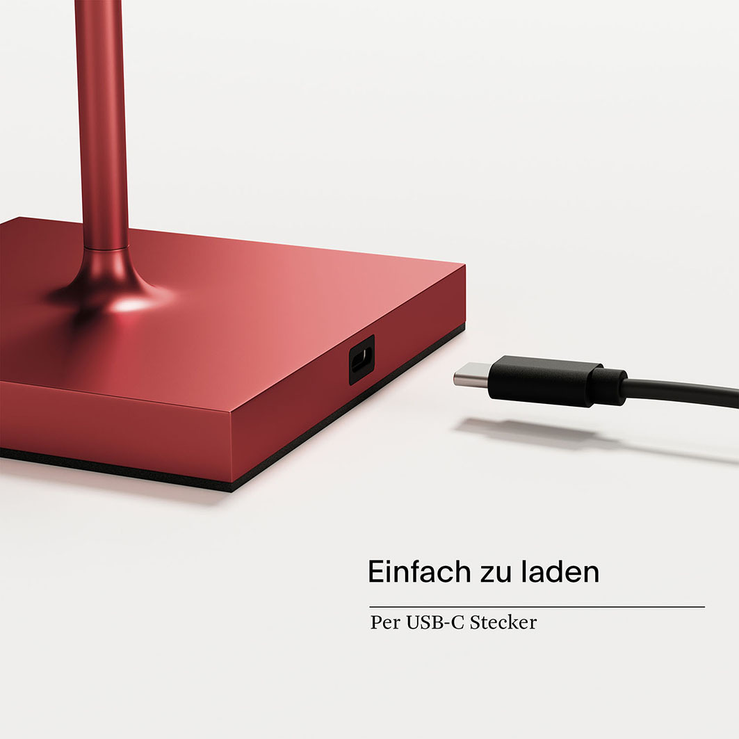 Ein roter Lampenfuß mit einem USB-C-Kabel daneben.