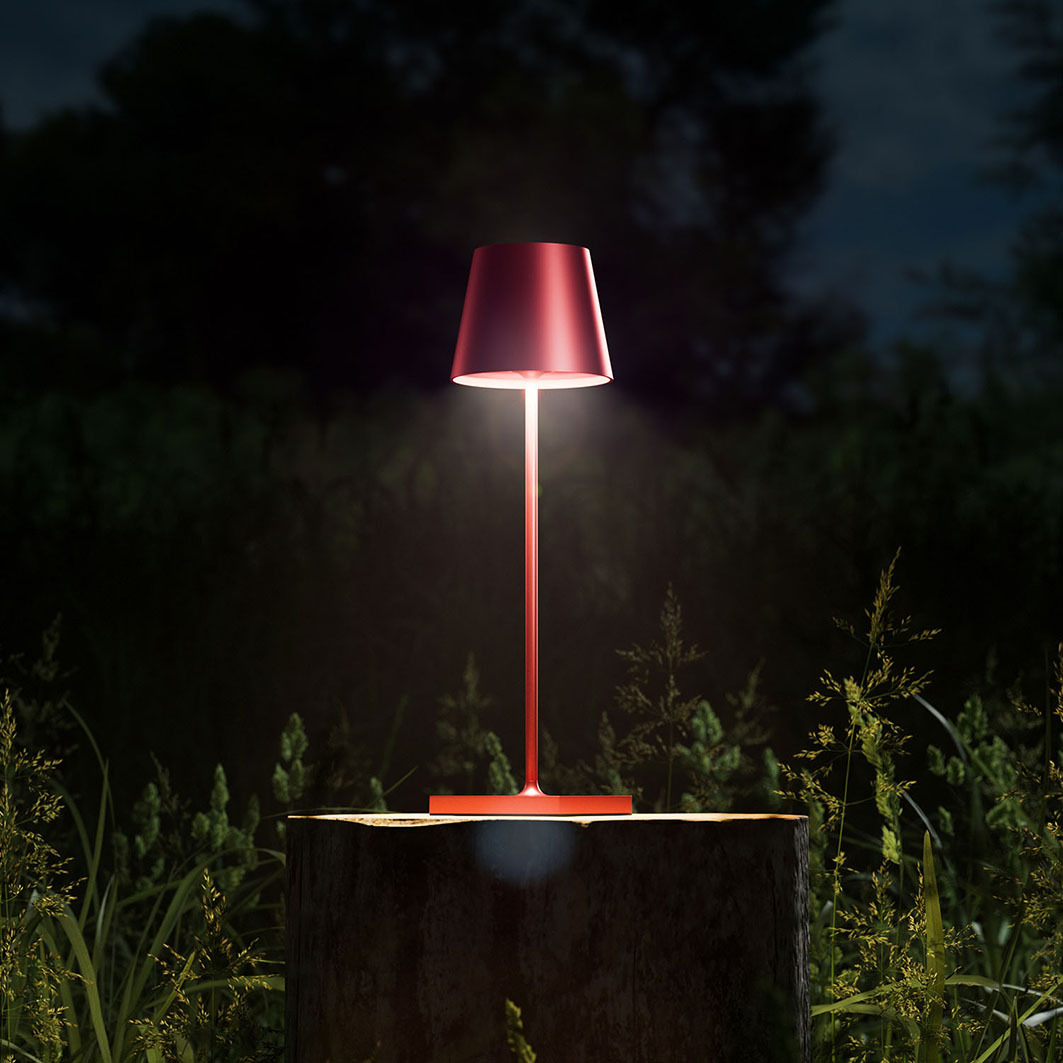 Eine rote Lampe leuchtet auf einem Baumstumpf im Freien bei Nacht.