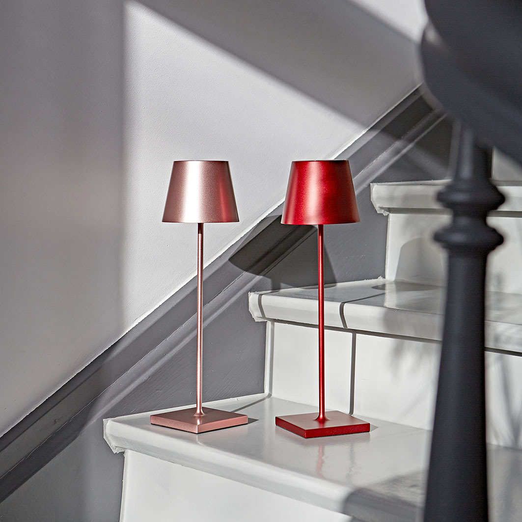 Zwei moderne Lampen, eine rosegold und eine rot, auf einer Treppe.