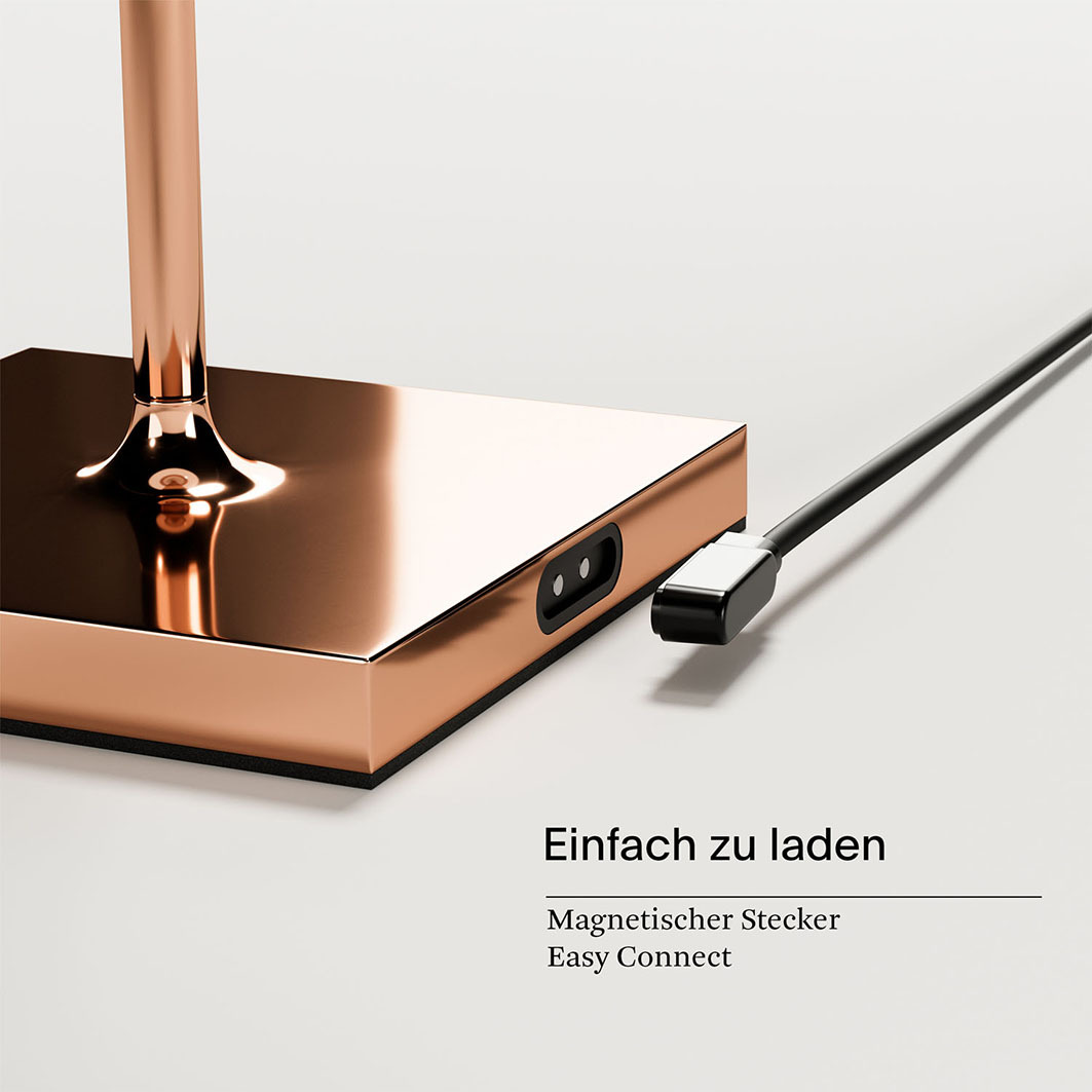 Eine kupferfarbene Bodenlampe mit magnetischem Ladekabel.
