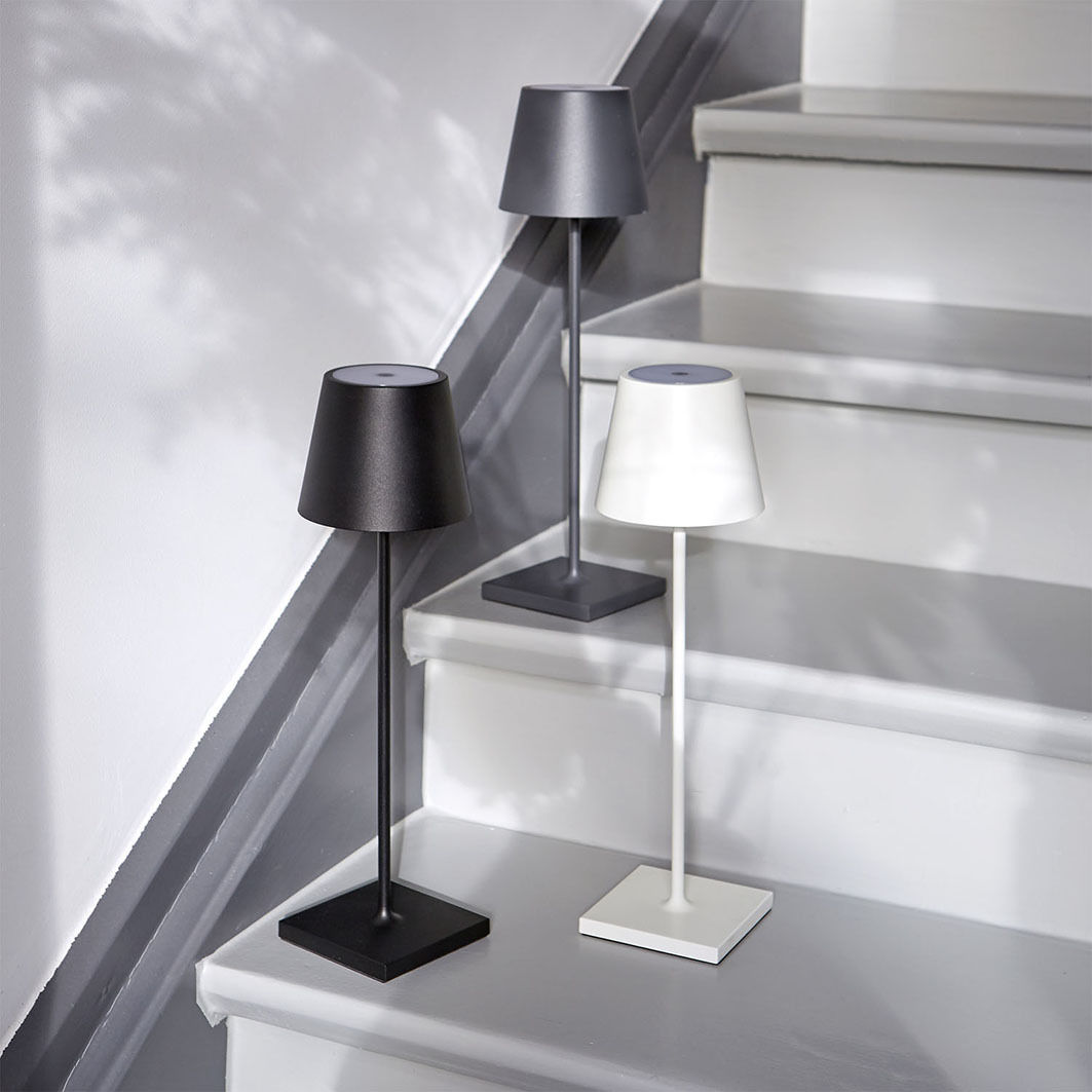 Drei moderne Lampen in Schwarz, Weiß und Grau auf einer Treppe.