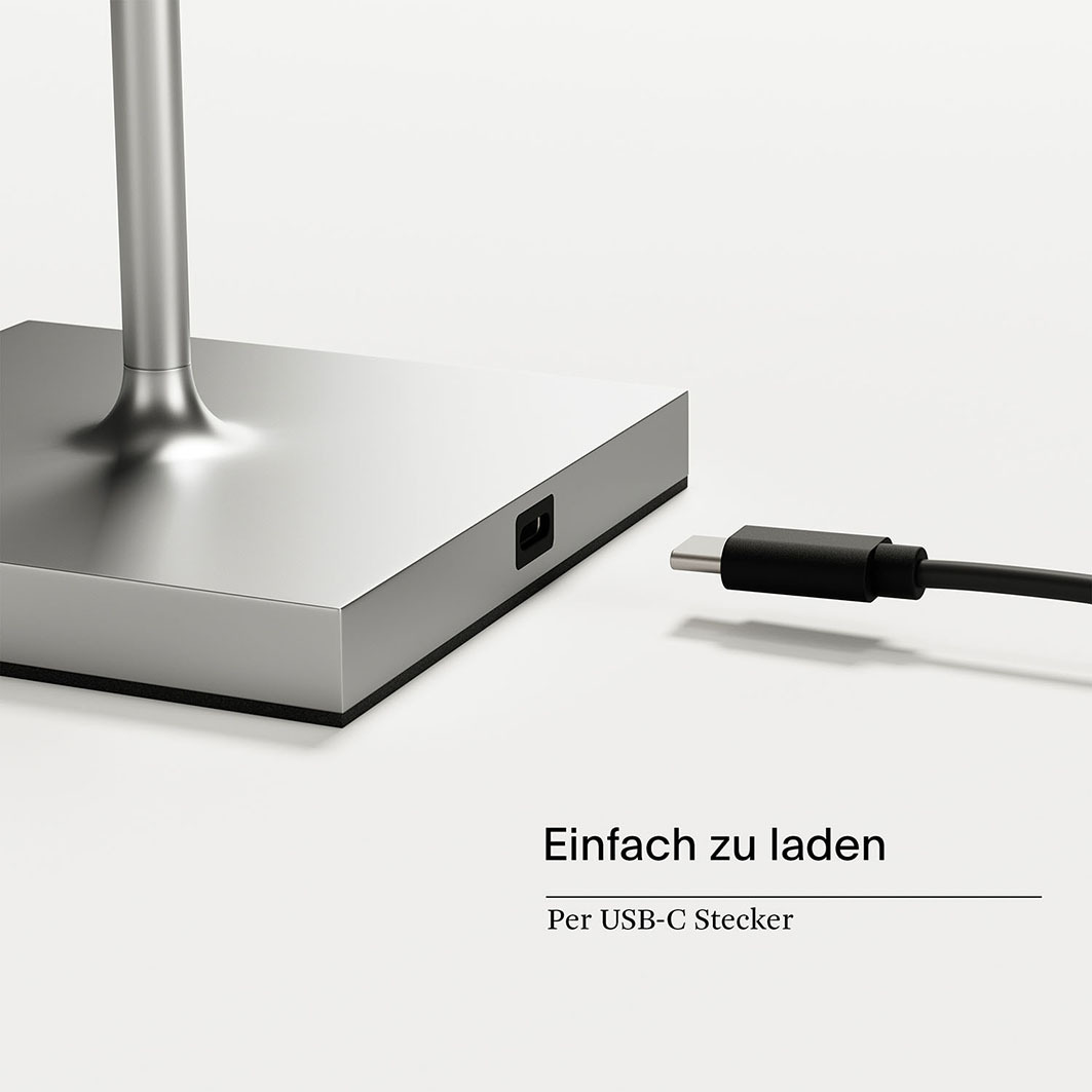 Ein Ladekabel mit USB-C-Stecker ist neben einer silbernen Basis mit Ladeanschluss.