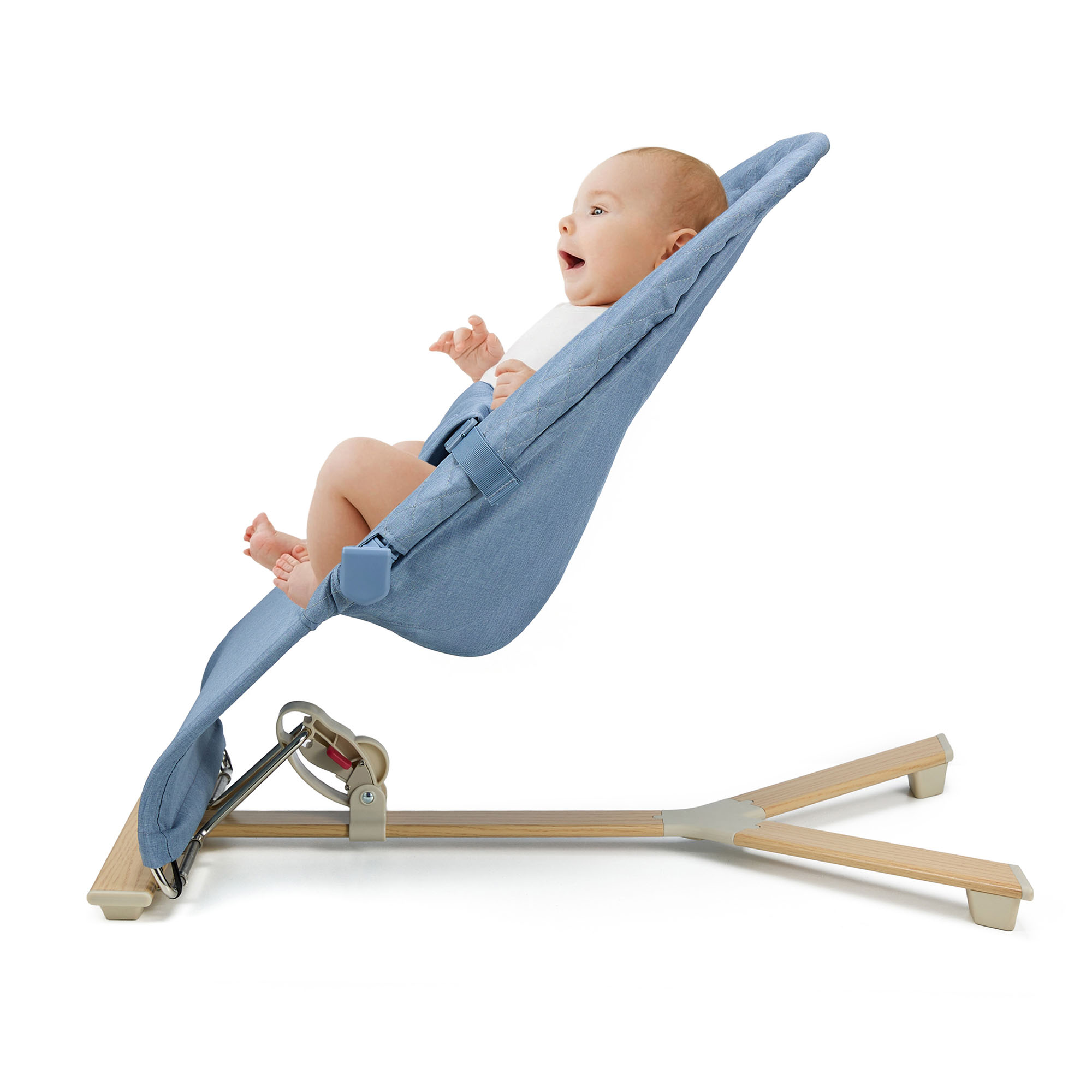 Ein Baby liegt in einer blauen Babywippe mit Holzrahmen.