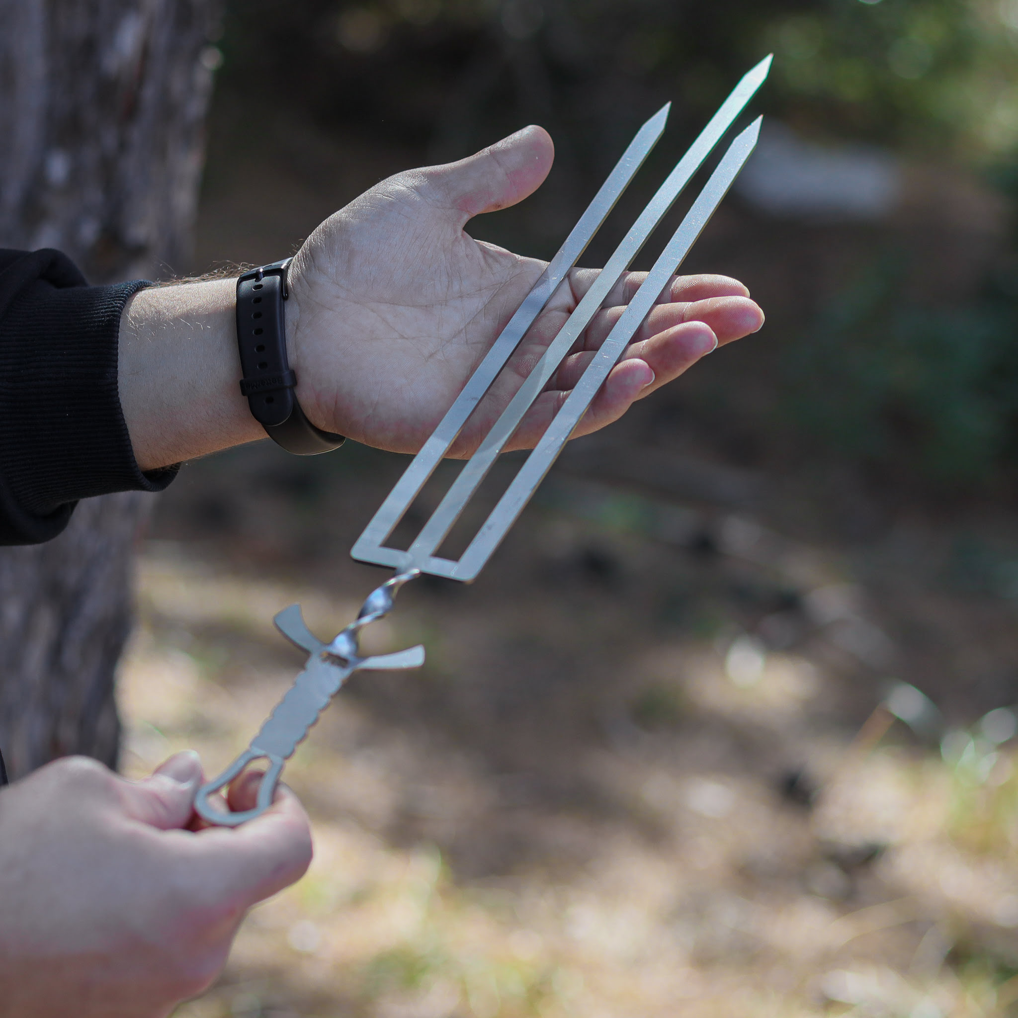 Bir el, üç uçlu ve burgulu saplı metal şiş tutuyor.